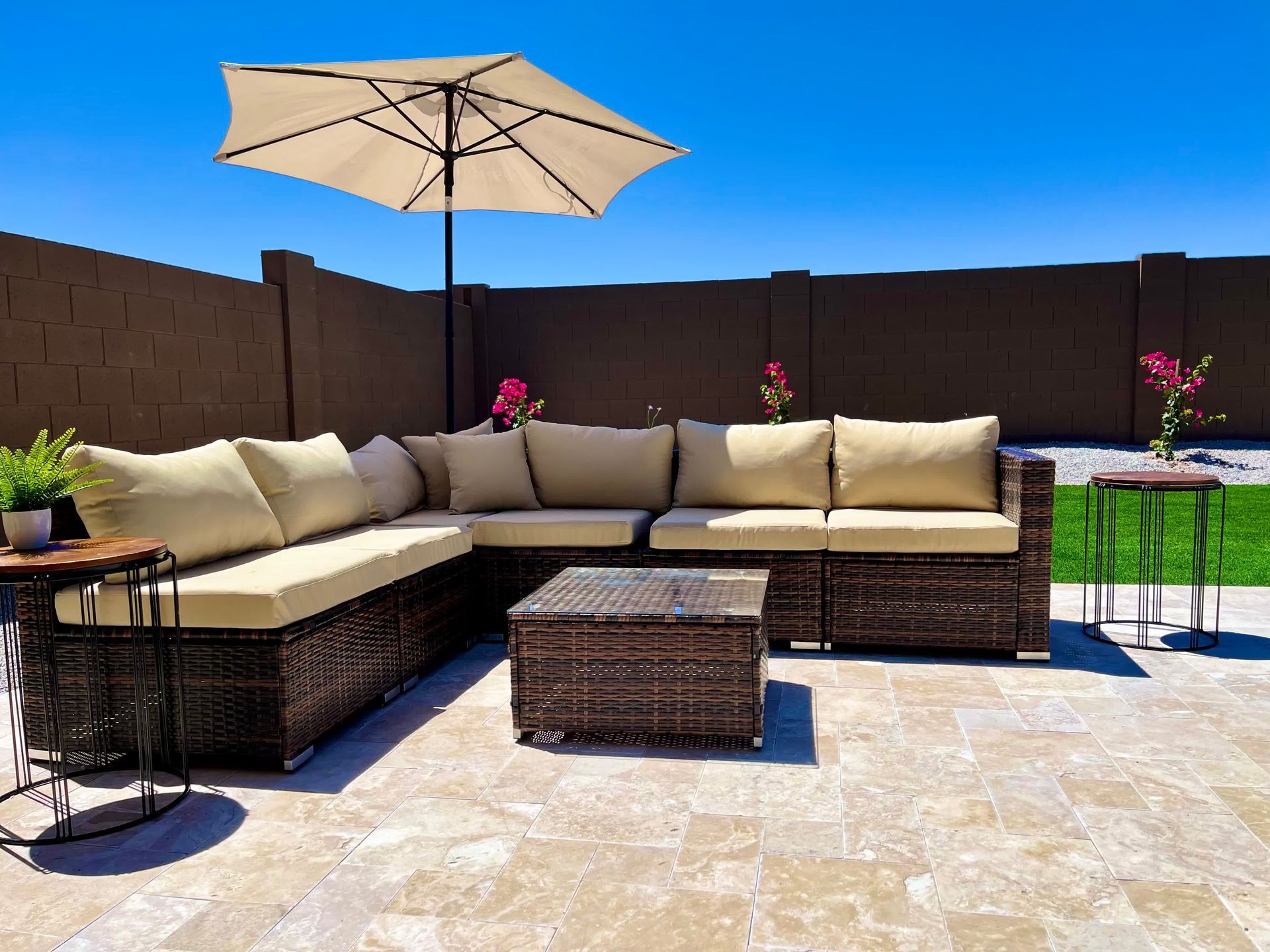 A patio with a sectional couch , coffee table , and umbrella.