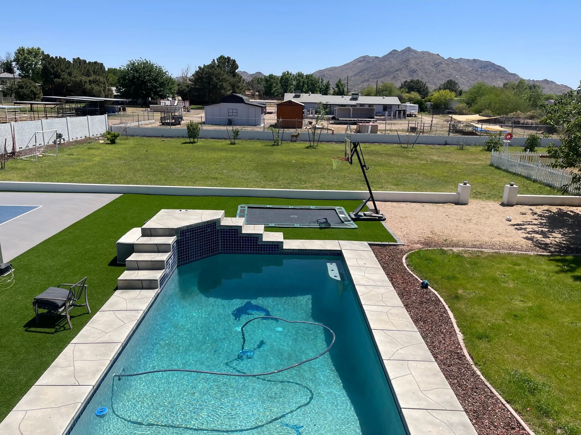 A large swimming pool in a backyard with mountains in the background