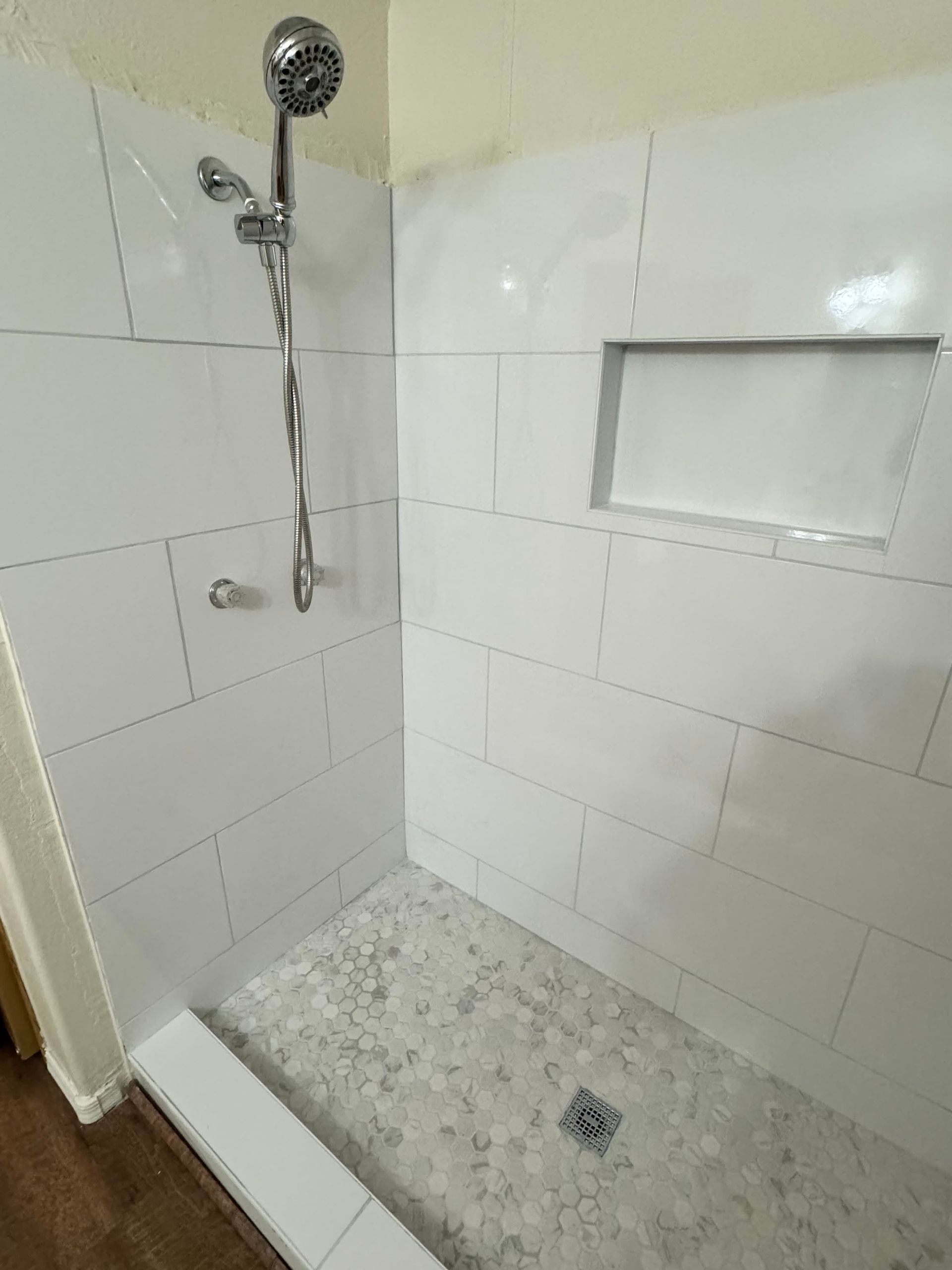 A bathroom with a walk in shower and a shower head.