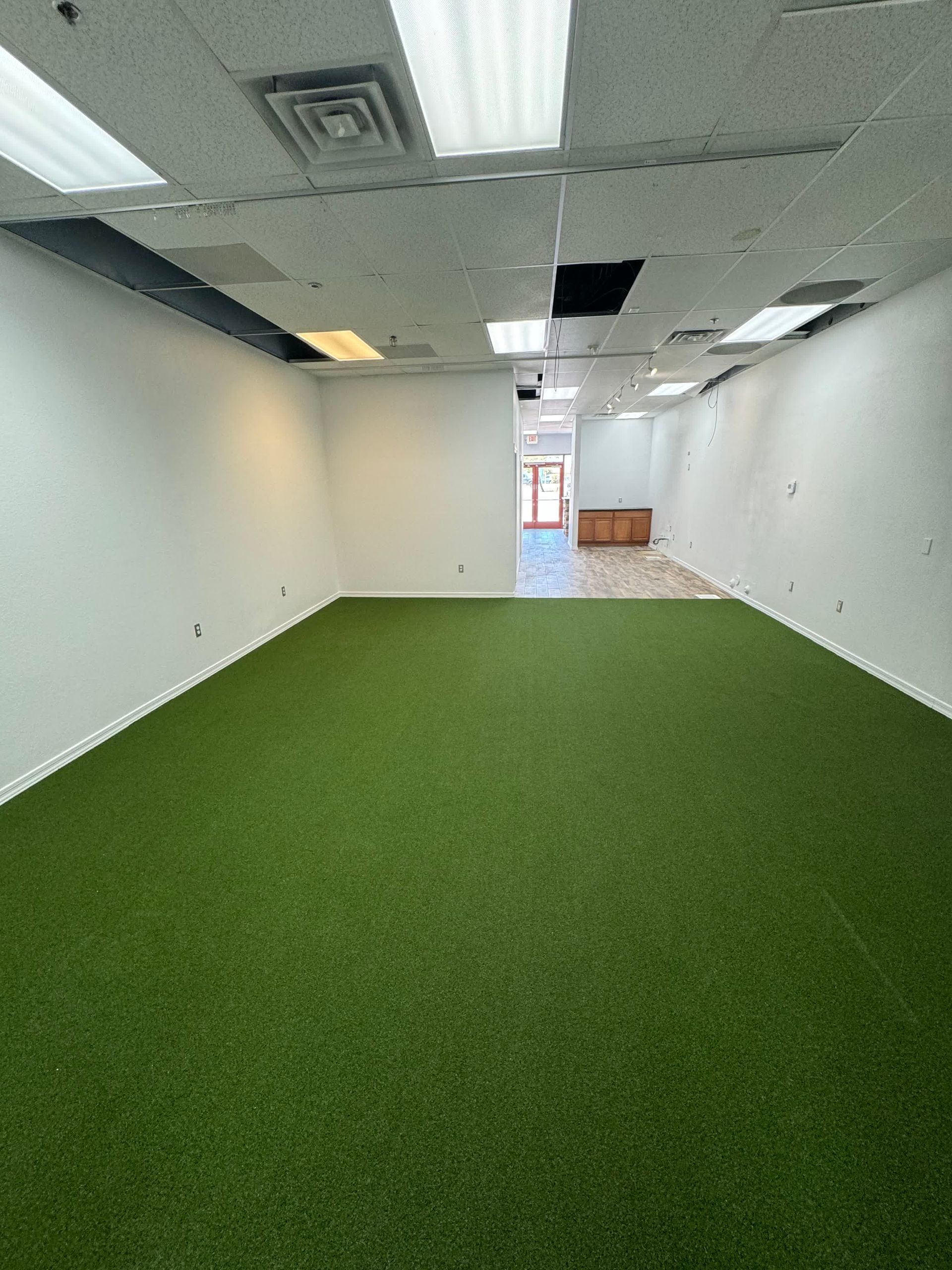 An empty room with a green carpet and white walls.