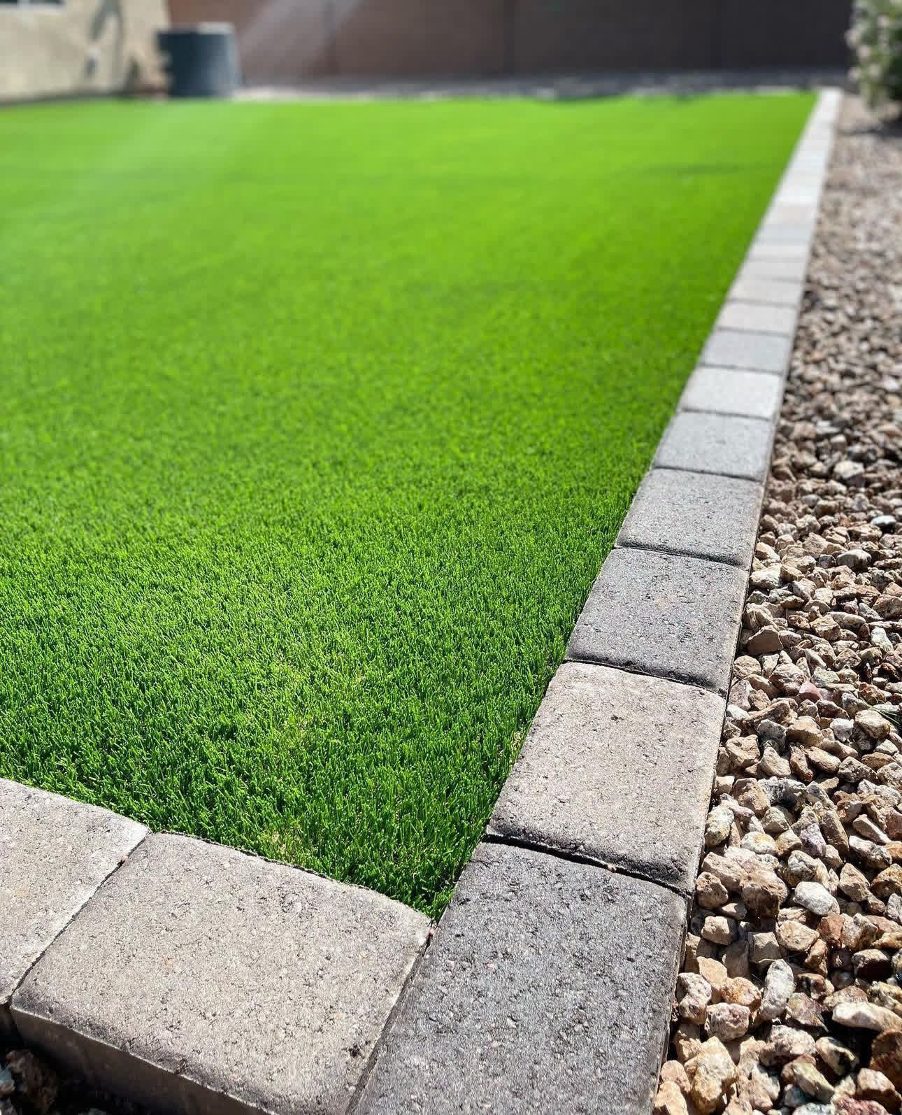 A close up of a lawn with a brick border and gravel.
