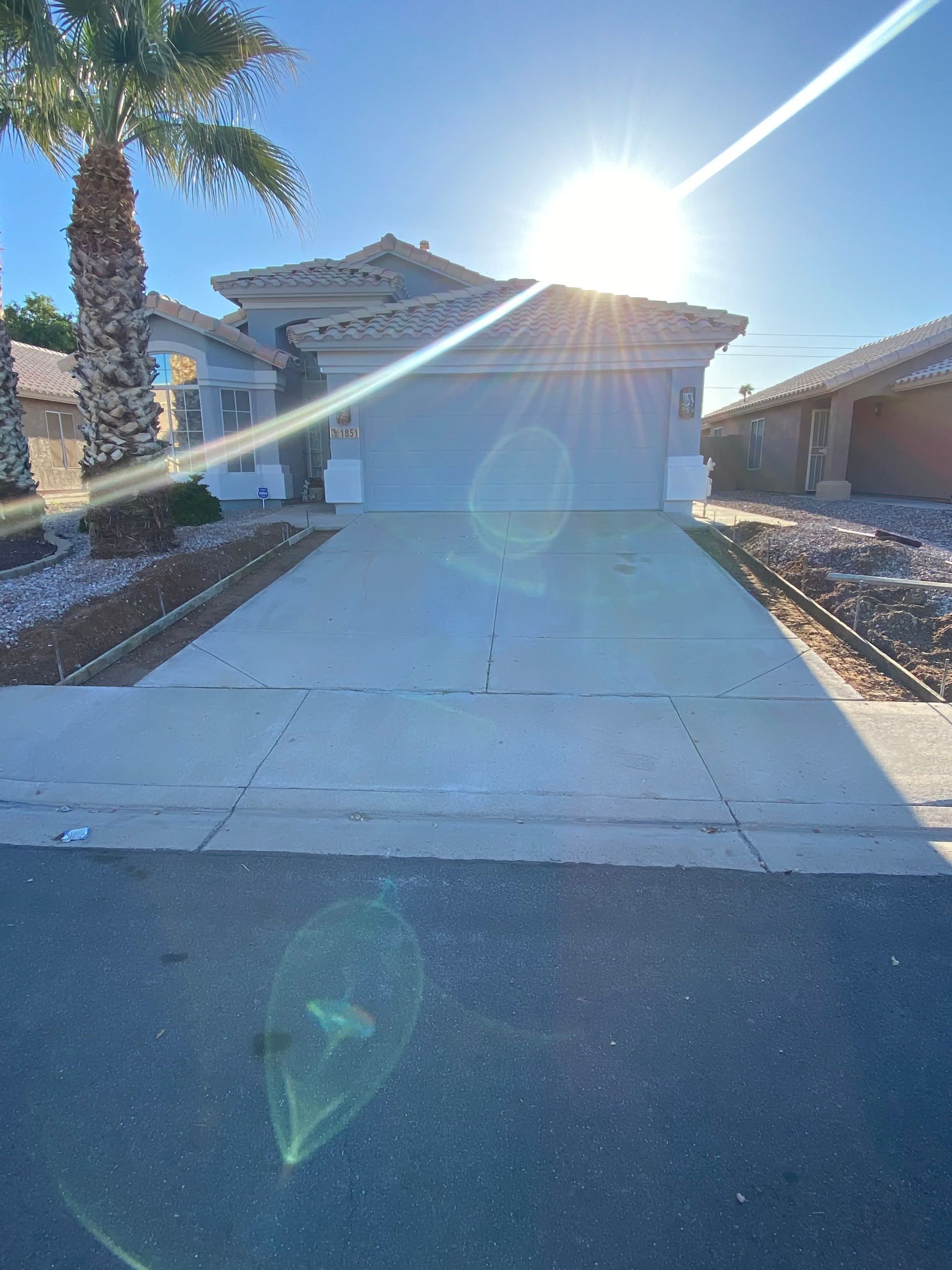 A house with a driveway and a palm tree in front of it