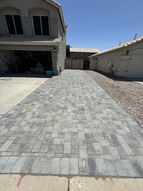 A brick driveway leading to a house on a sunny day