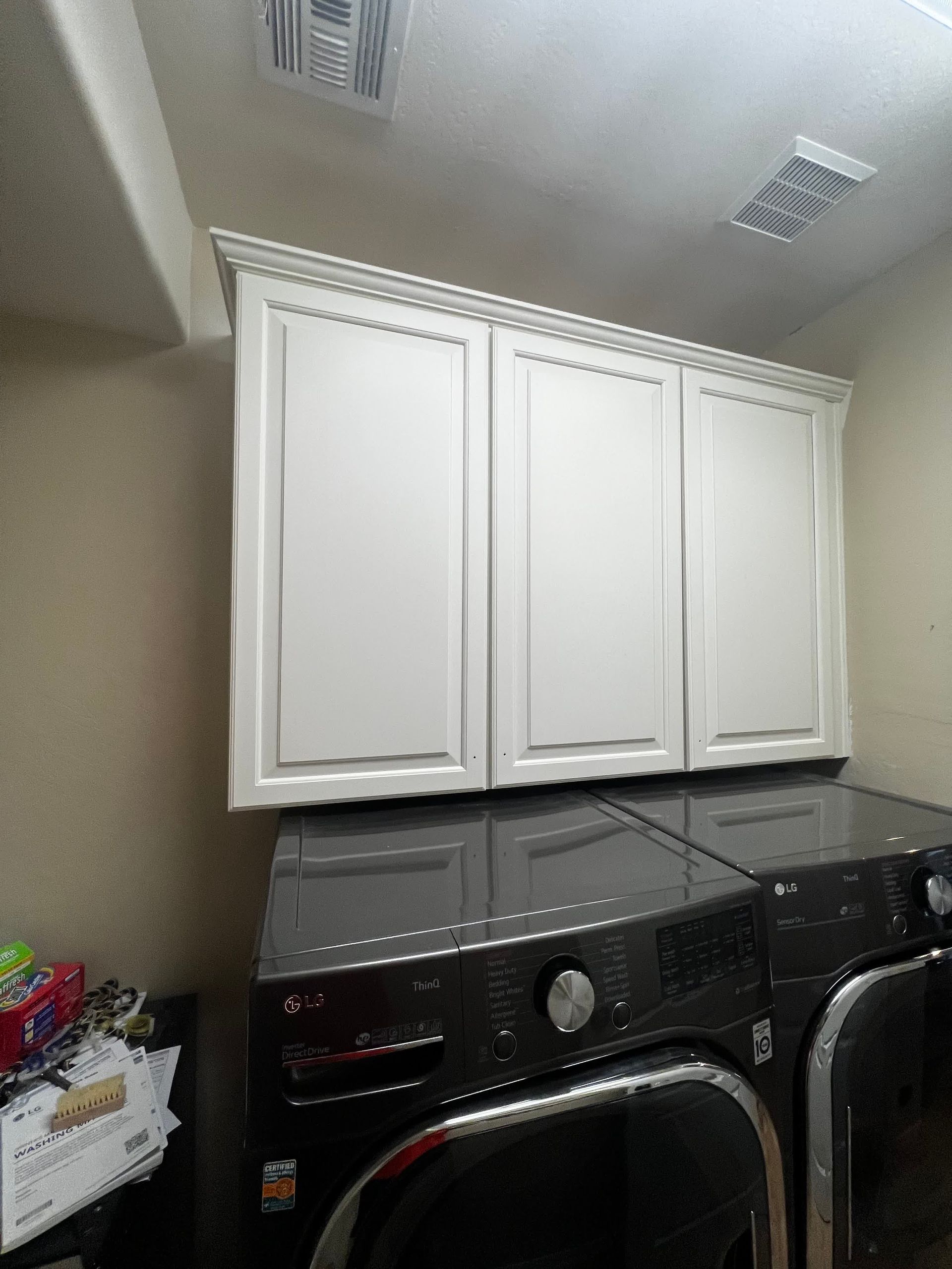 A laundry room with a washer and dryer and white cabinets.