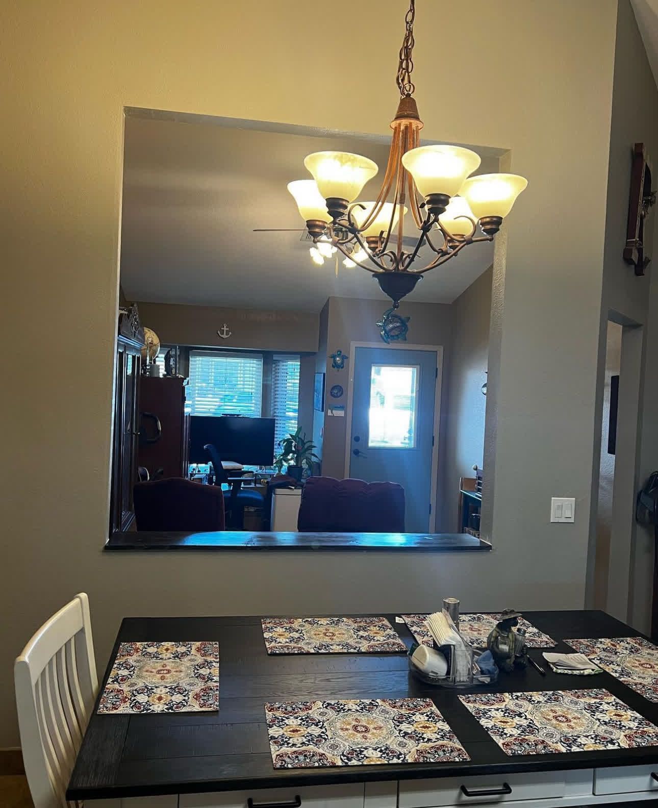 A dining room table with a chandelier hanging from the ceiling