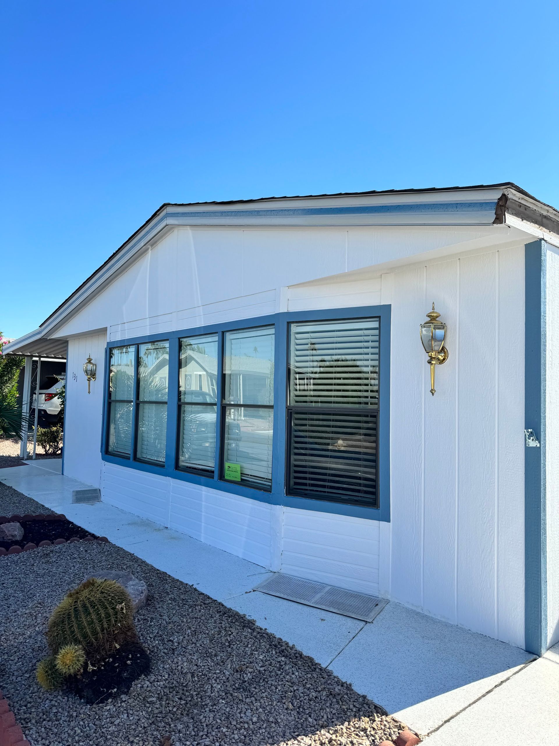 A white mobile home with blue windows and a blue roof