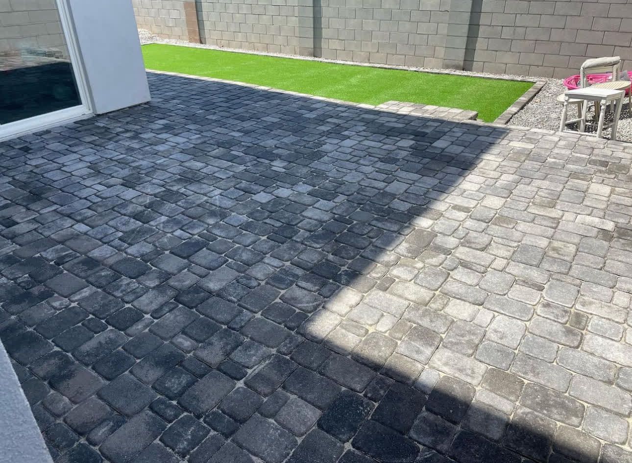 A patio with a table and chairs and a brick wall in the background.