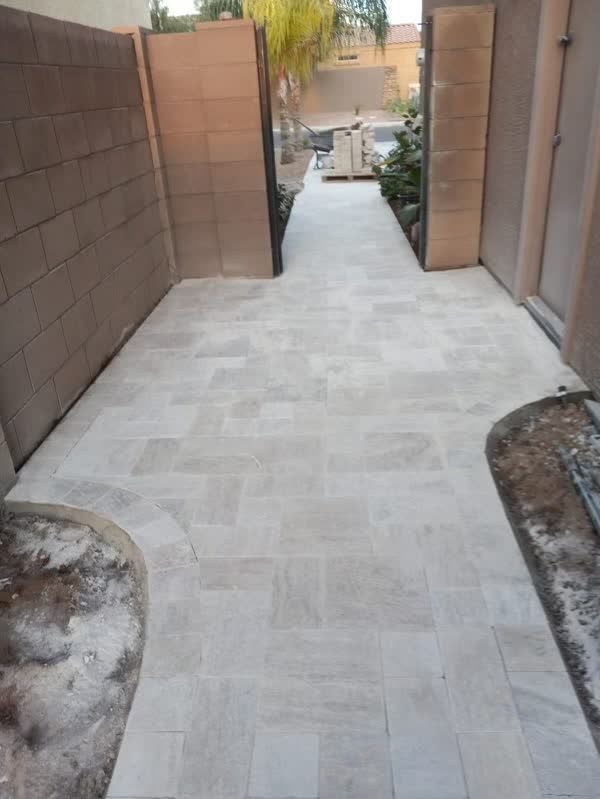 A white tiled walkway leading to a brick wall