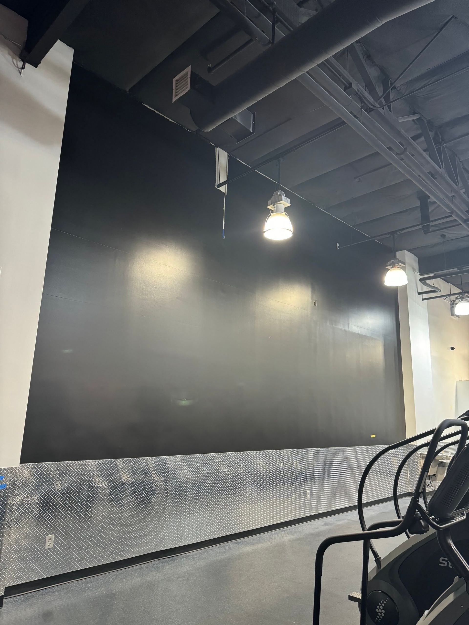 A gym with a large black wall and stairs