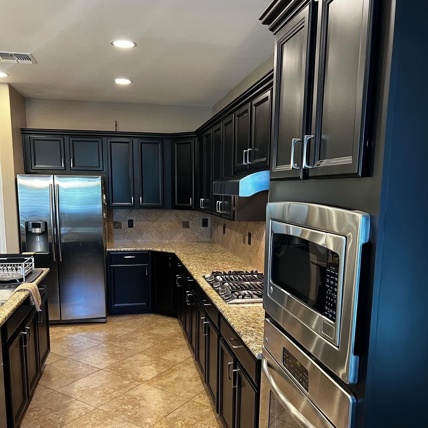 A kitchen with black cabinets and stainless steel appliances