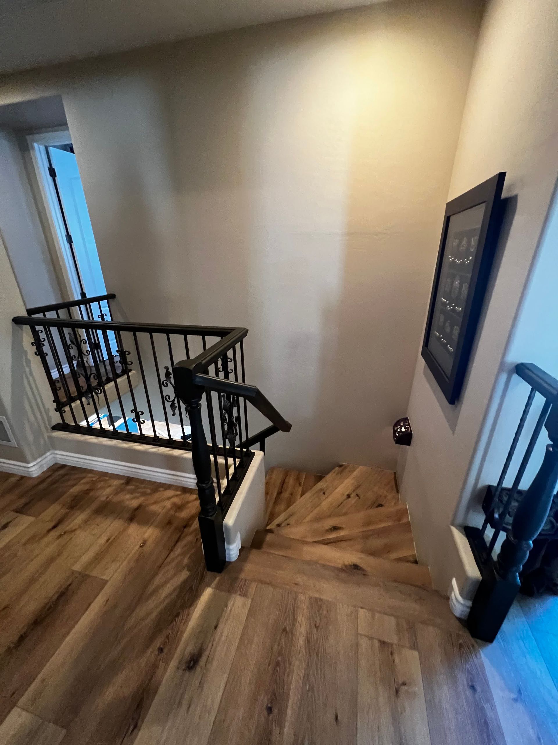 A wooden staircase with a black railing and a picture on the wall.