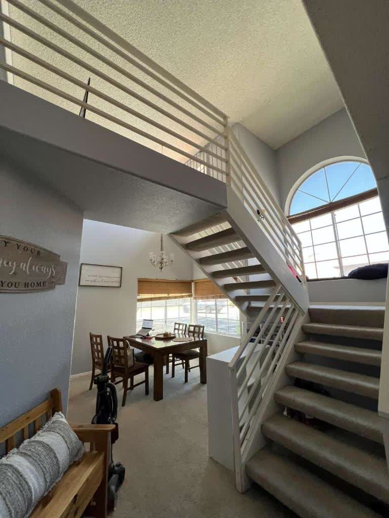 A living room with stairs leading up to the second floor and a table and chairs.
