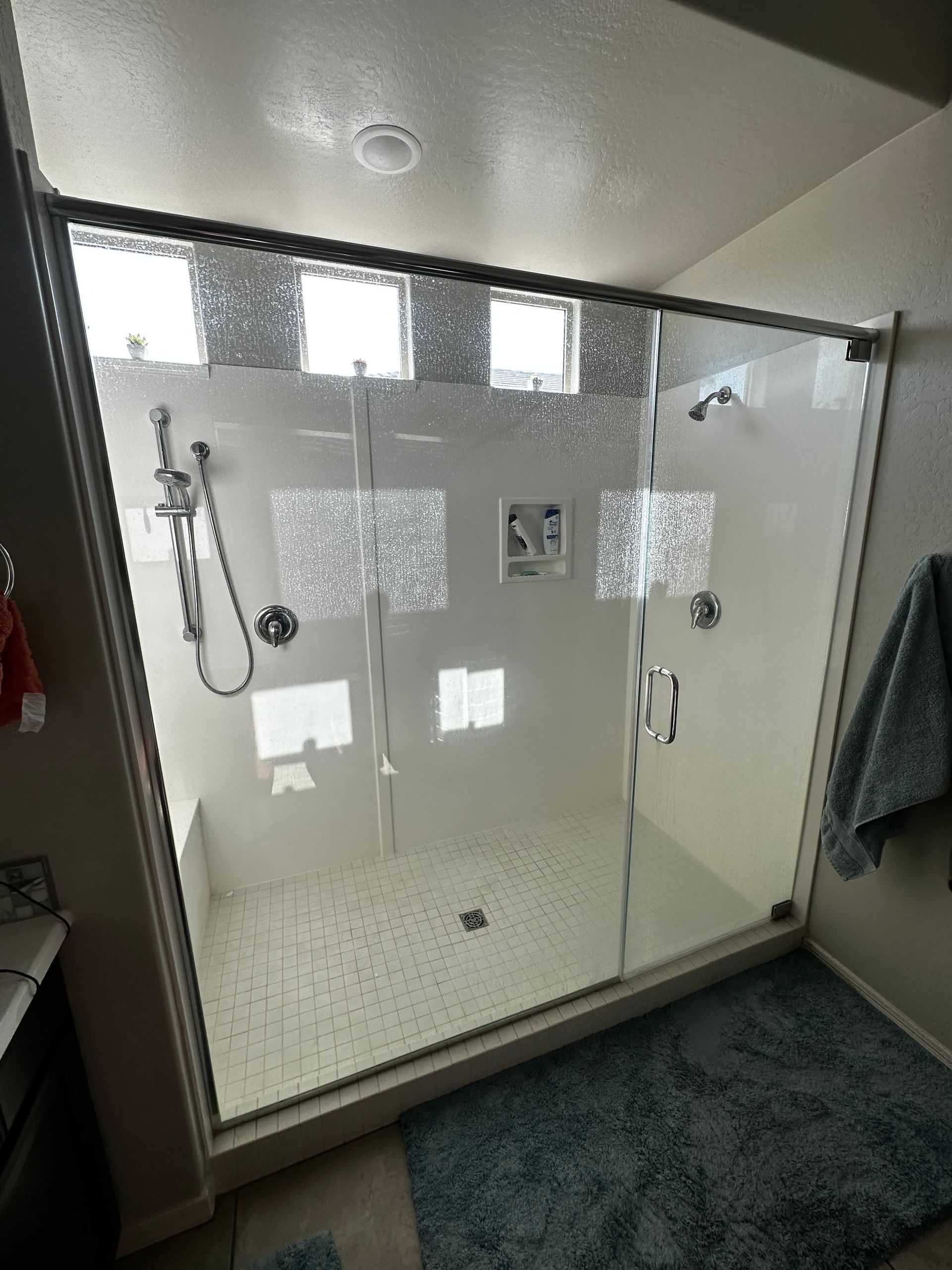 A bathroom with a walk in shower with sliding glass doors.