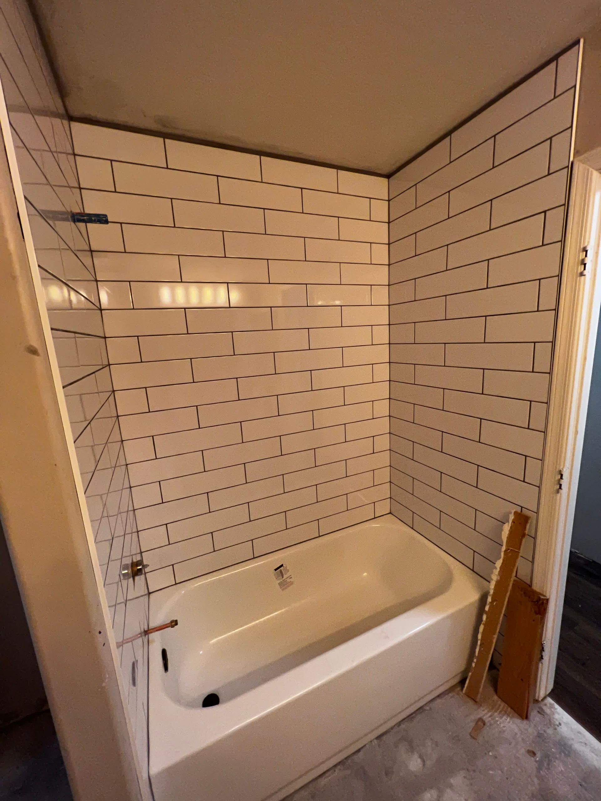 A bathtub in a bathroom with white tiles on the wall
