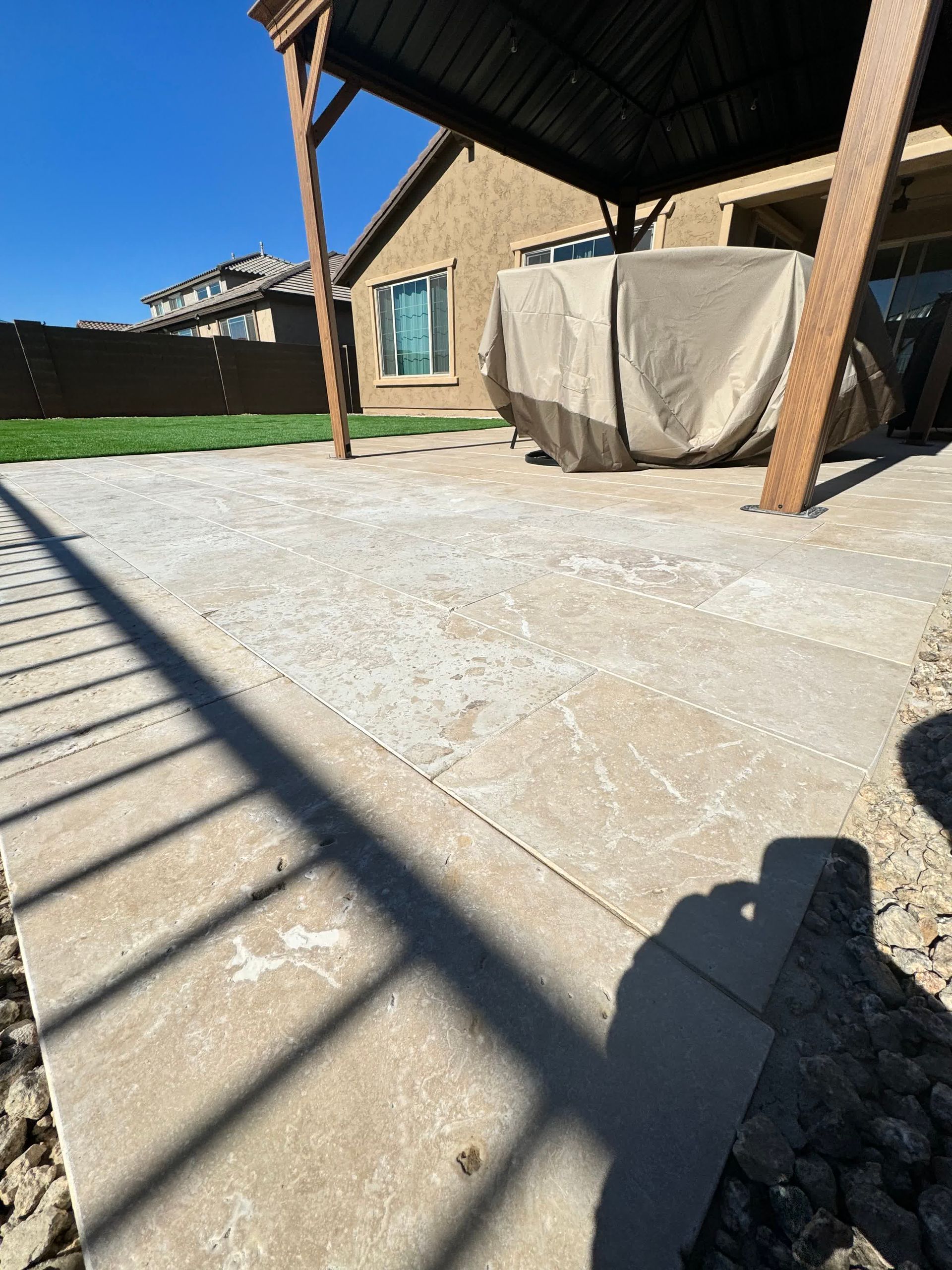A patio with a gazebo and a hot tub underneath it.