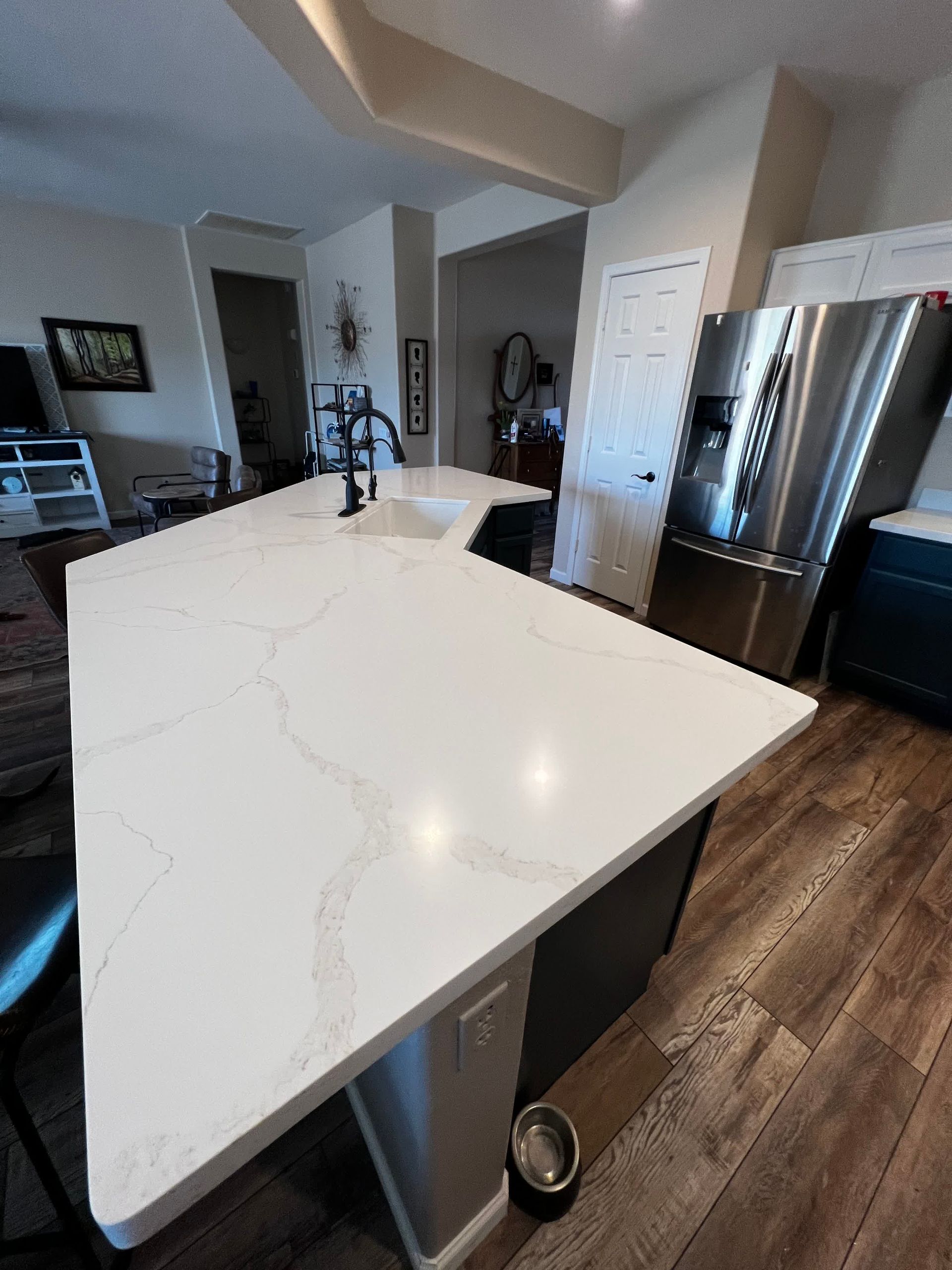 A kitchen with a large white counter top and stainless steel appliances.