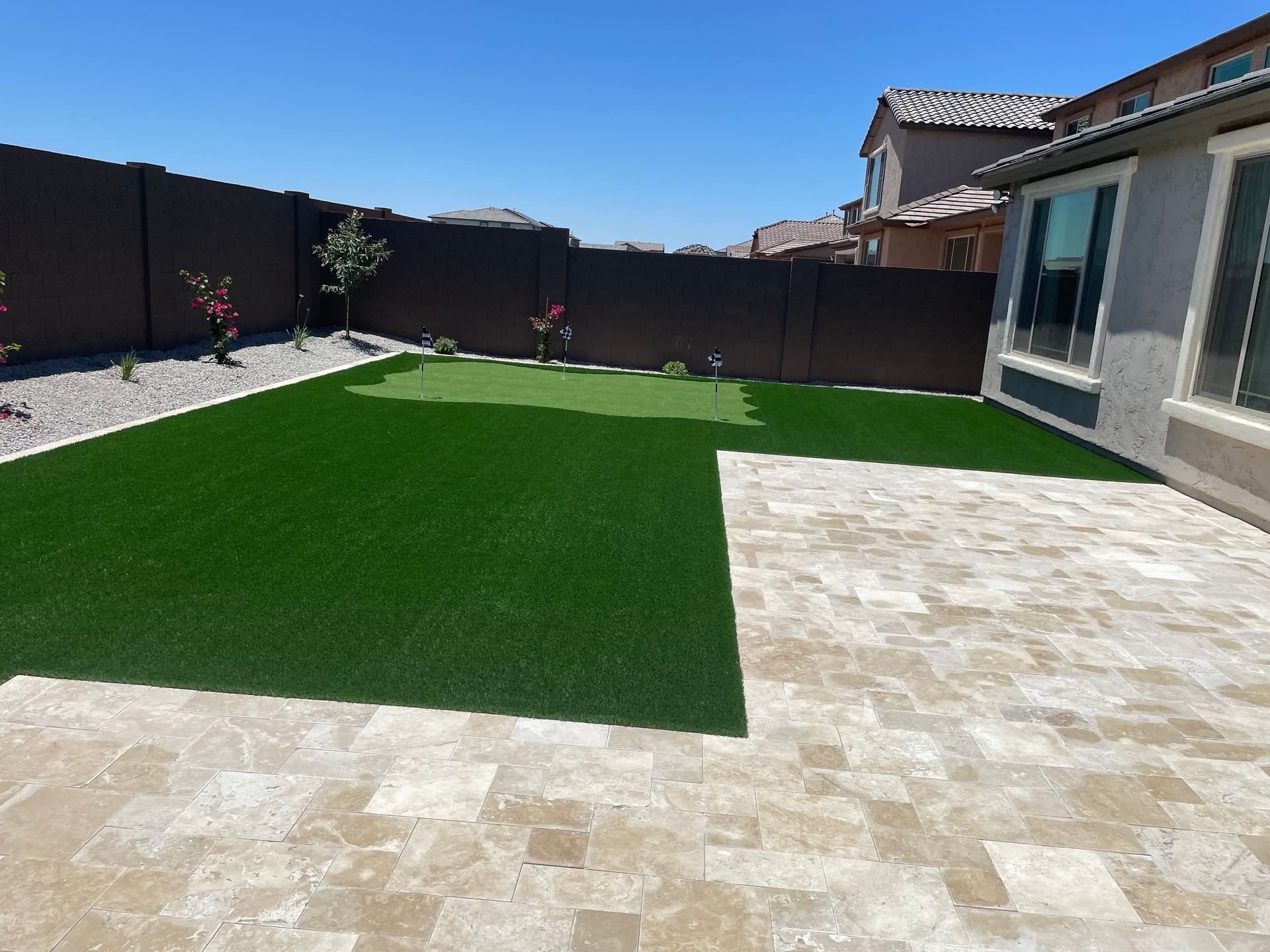 A backyard with a putting green and a patio