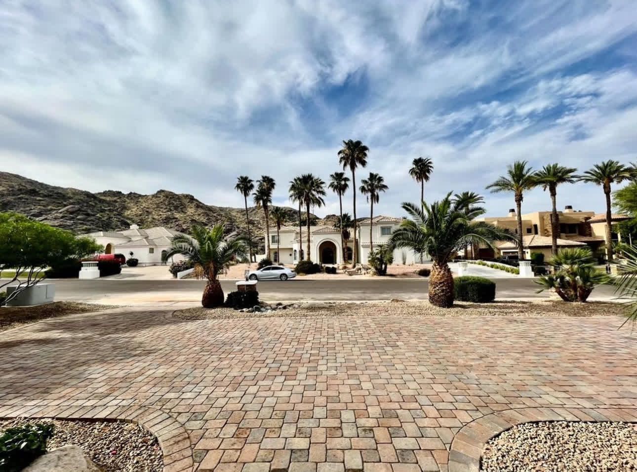 A brick driveway with palm trees in the background
