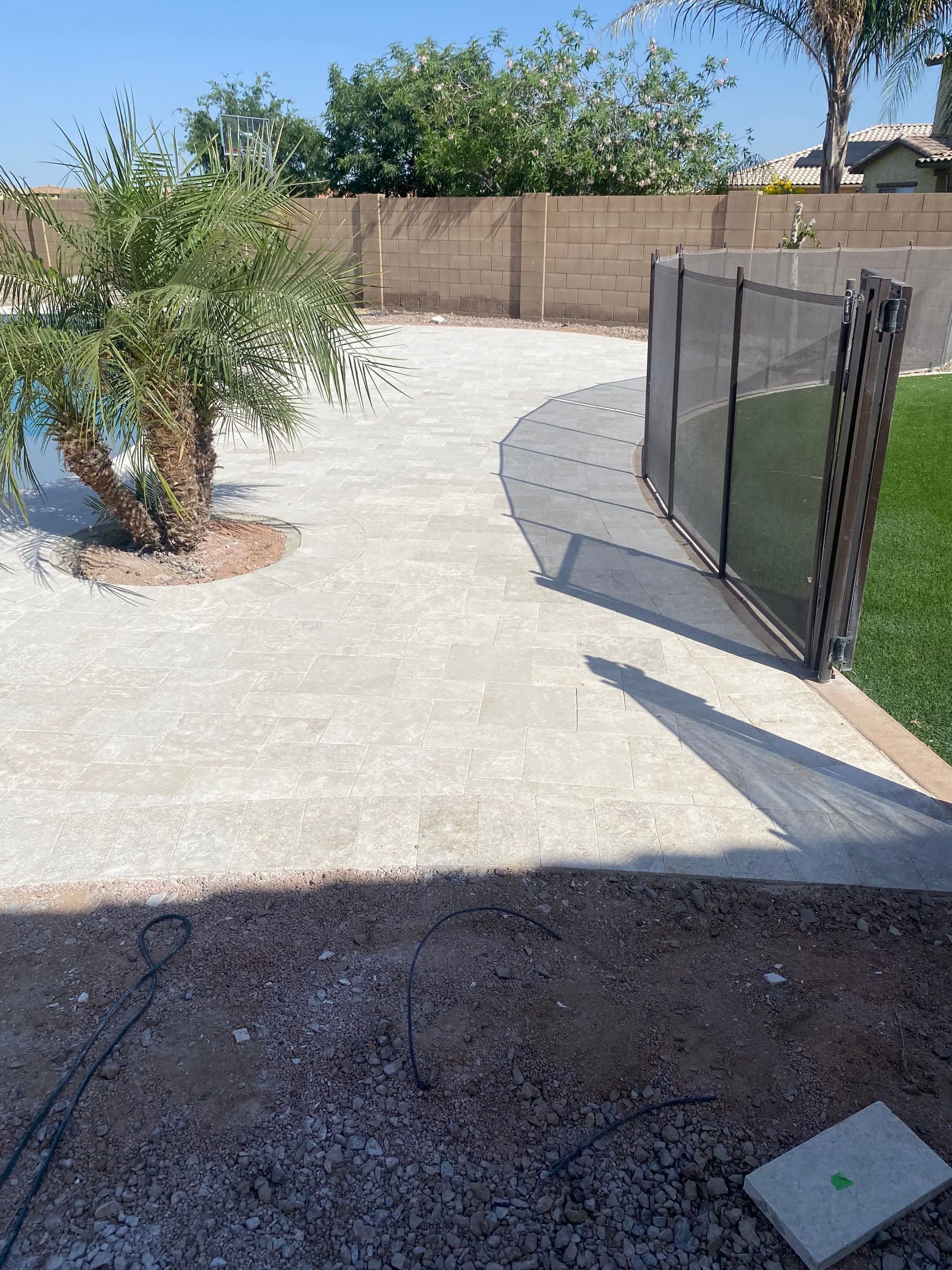 A backyard with a fence and a tree in the middle of it.