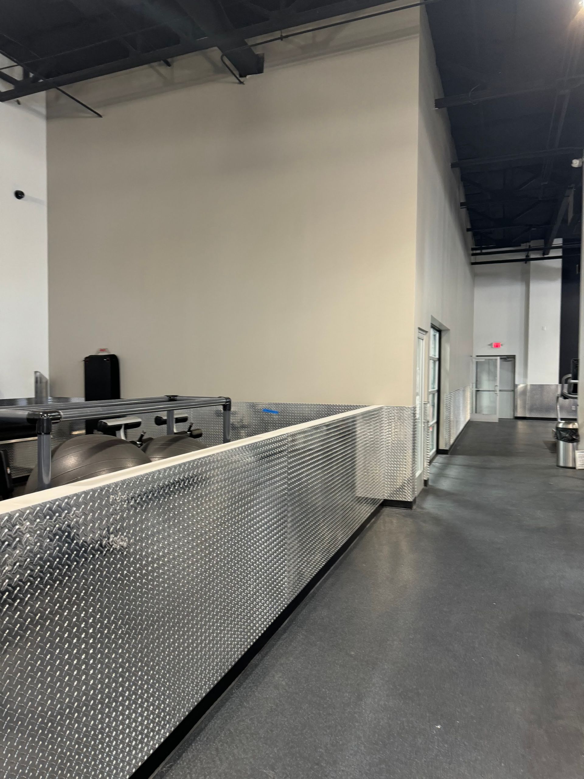 A long hallway in a gym with a metal fence.