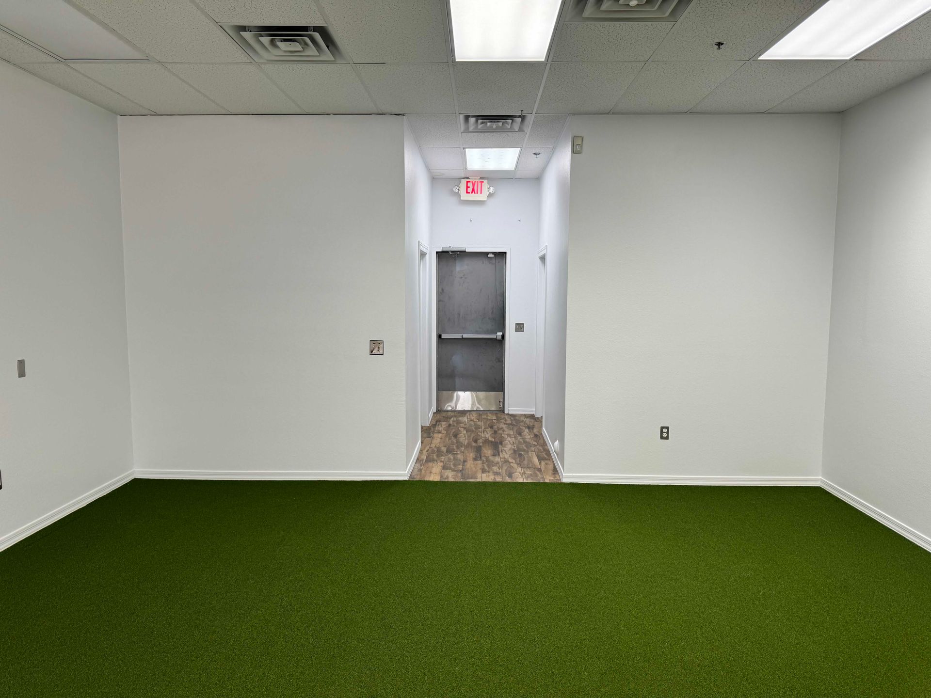 An empty room with a green carpet and white walls
