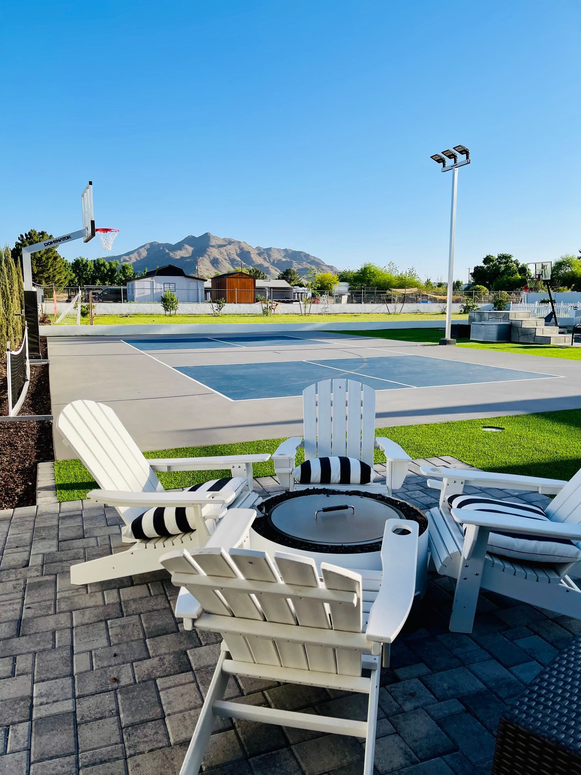 A patio with a table and chairs and a pool in the background