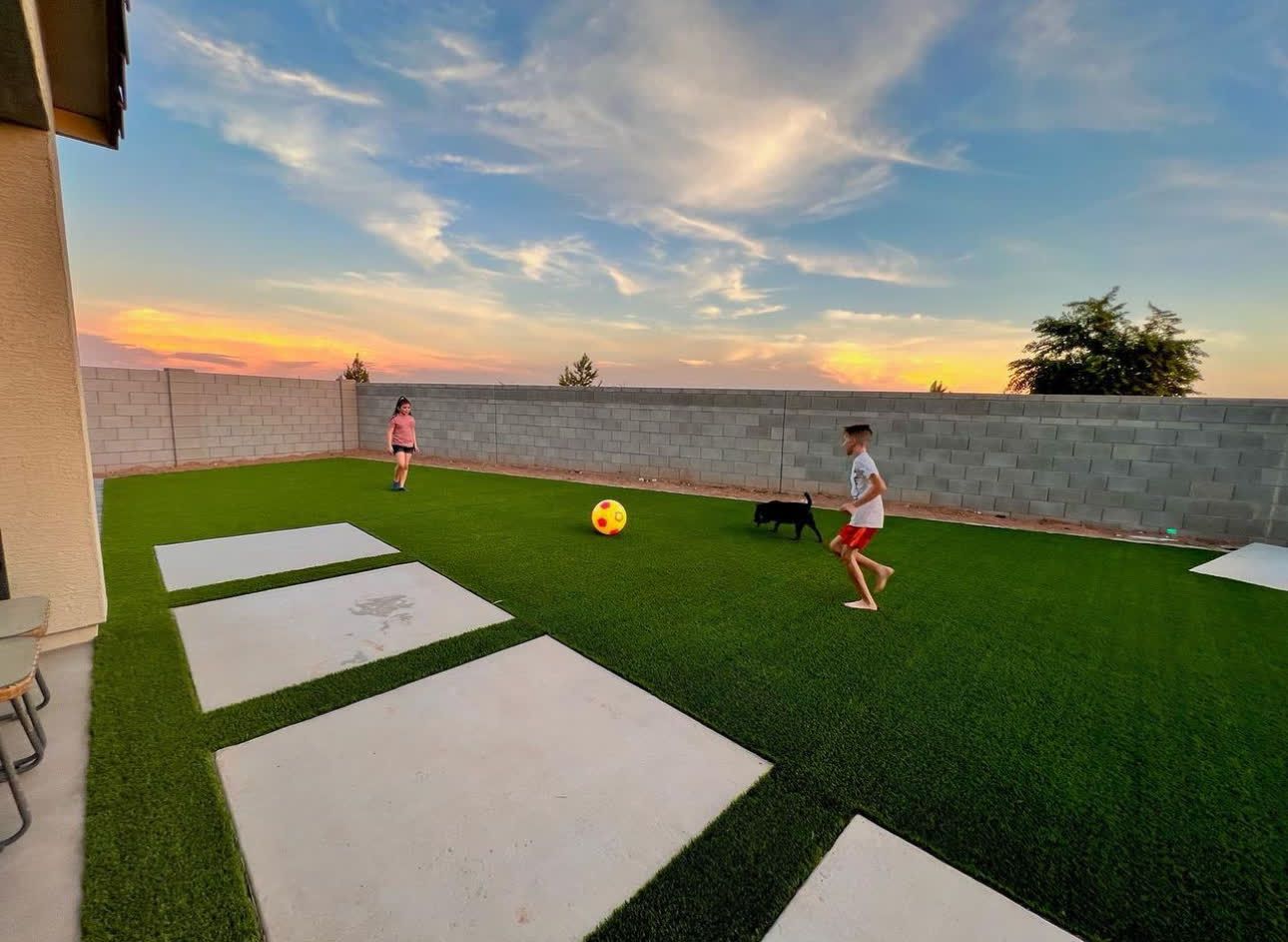 A boy and a girl are playing soccer in a backyard.