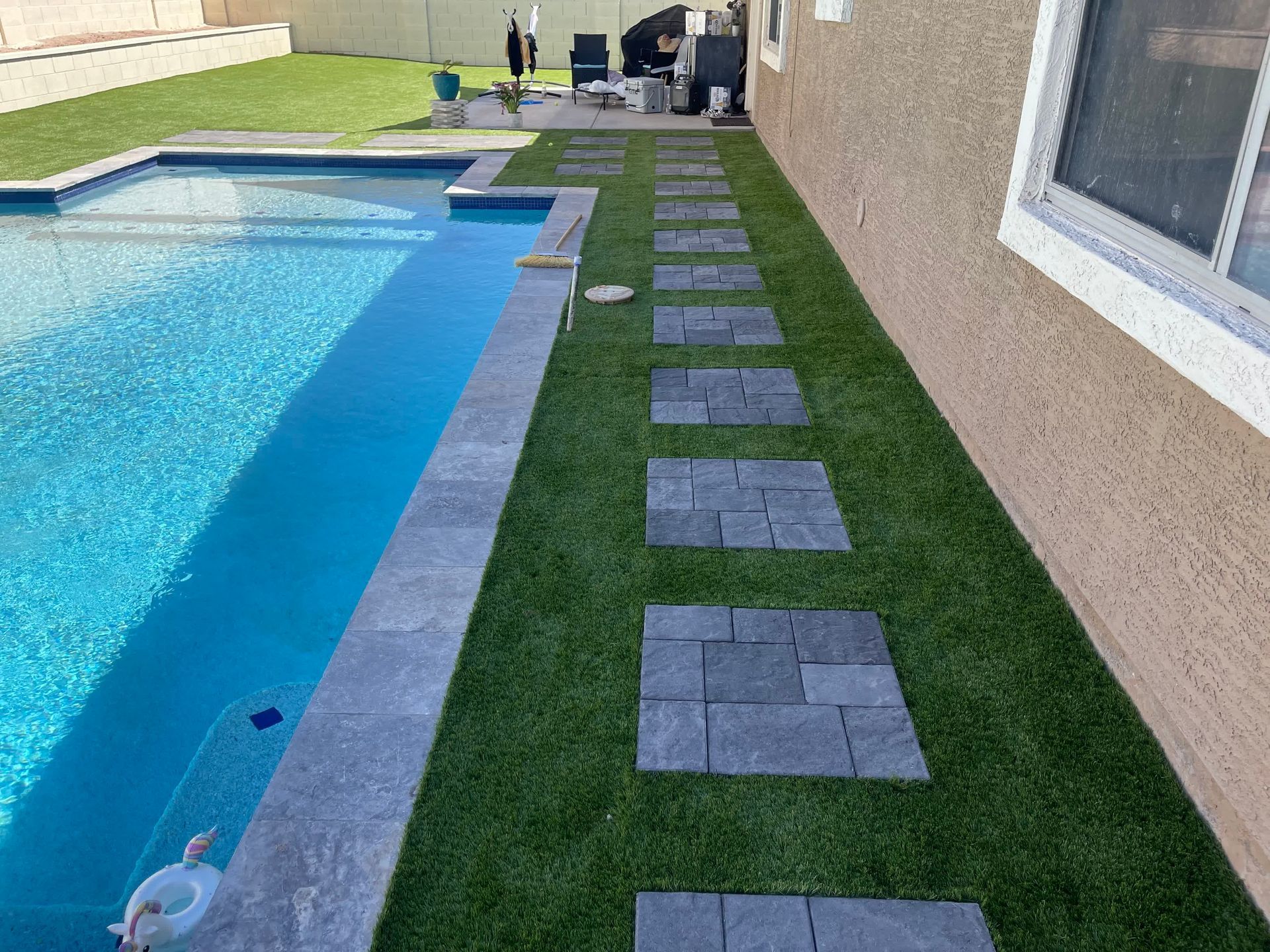 A swimming pool with a brick walkway leading to it.