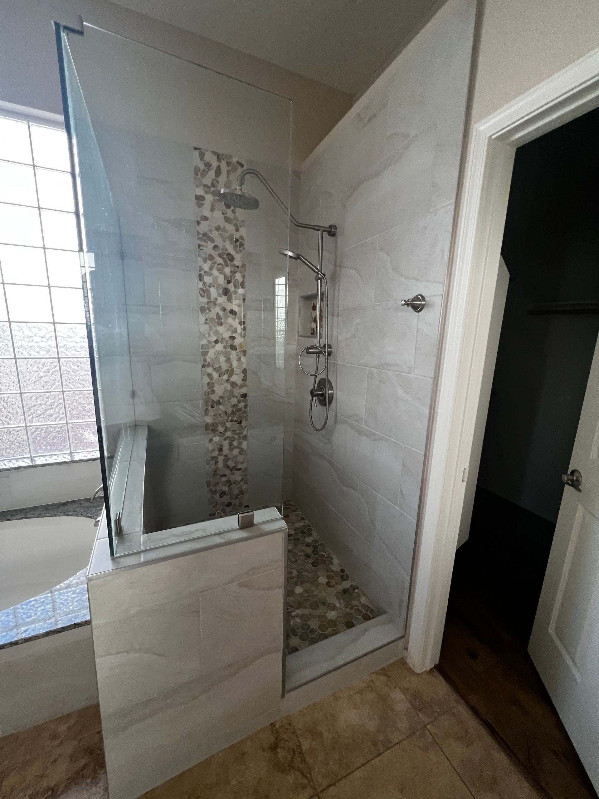 A bathroom with a walk in shower with a glass door.