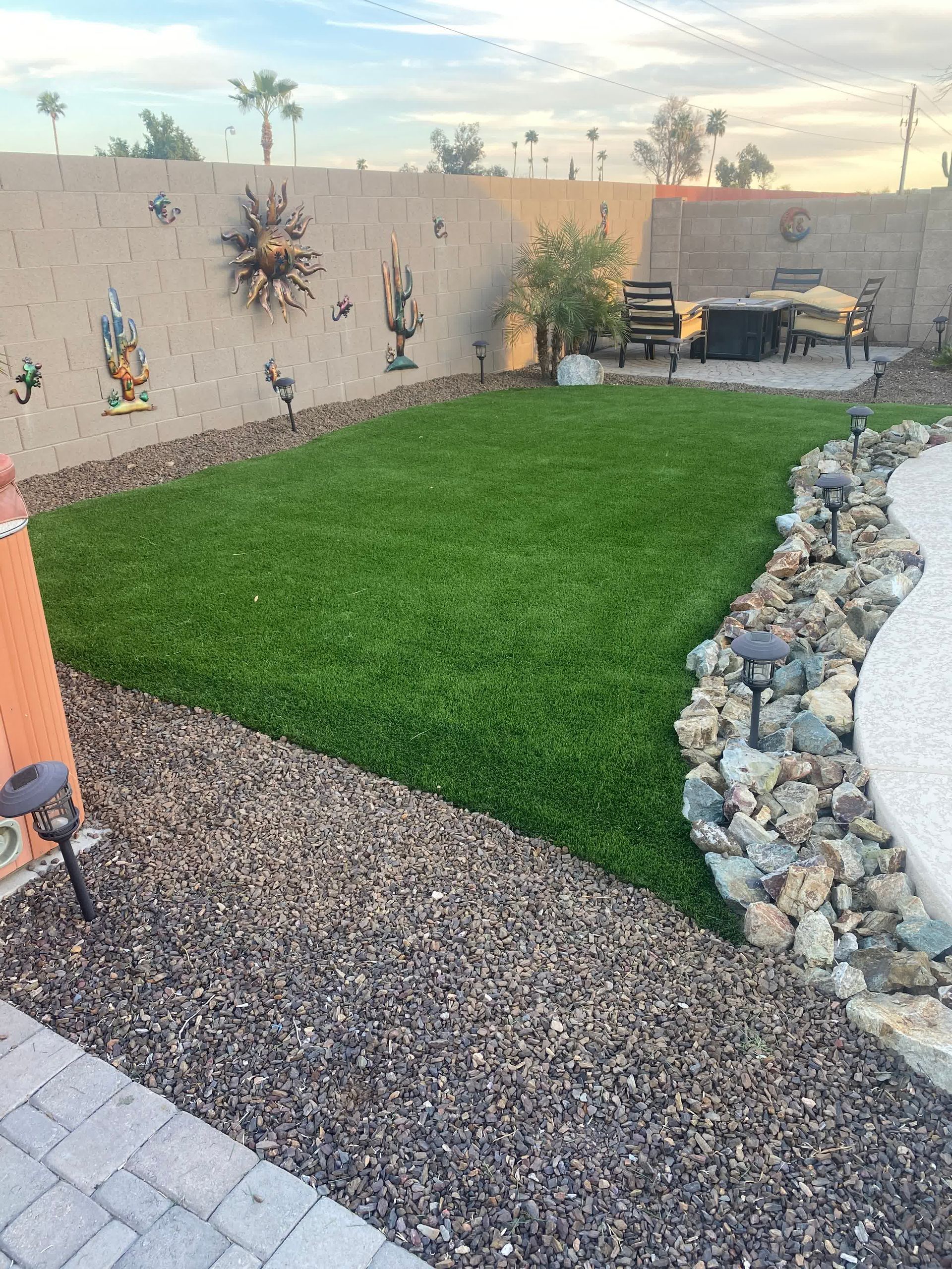A backyard with a lush green lawn and rocks.