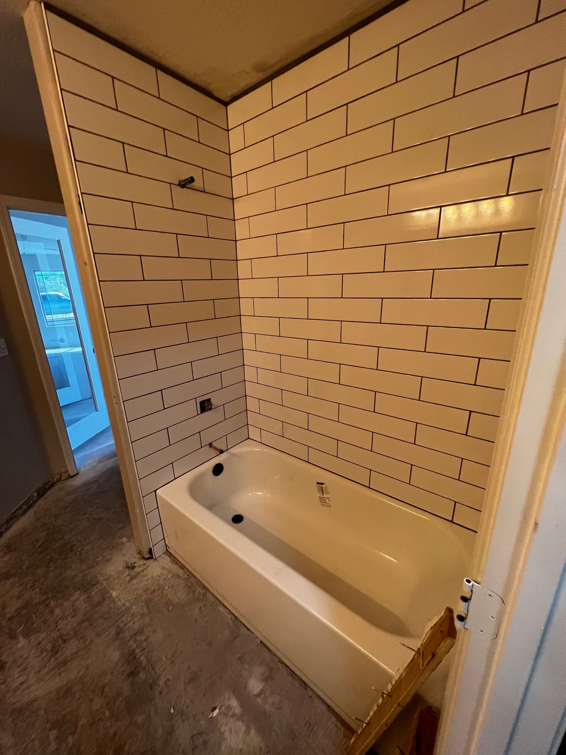A bathroom with a bathtub and a brick wall