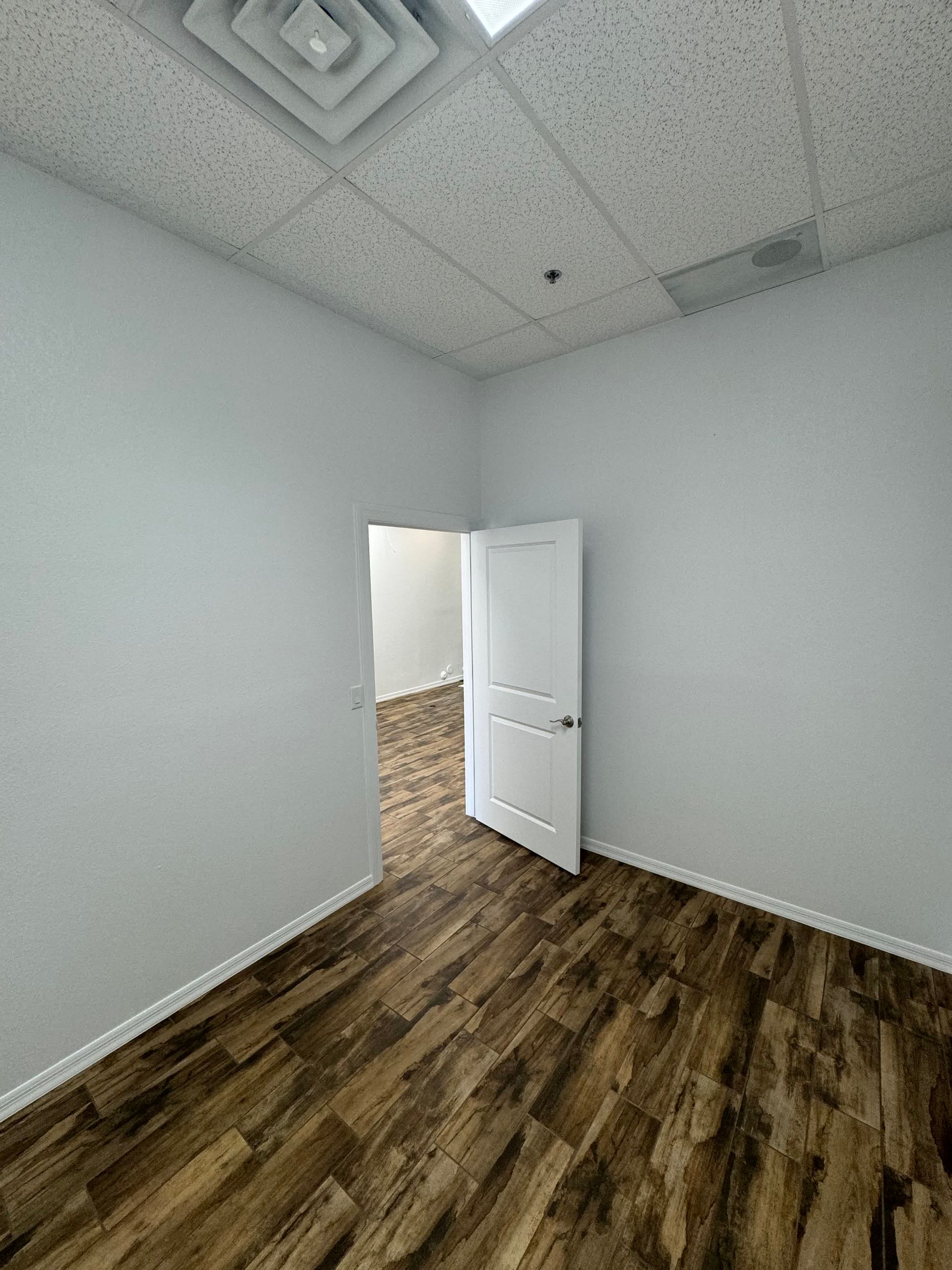 An empty room with a wooden floor and a white door.