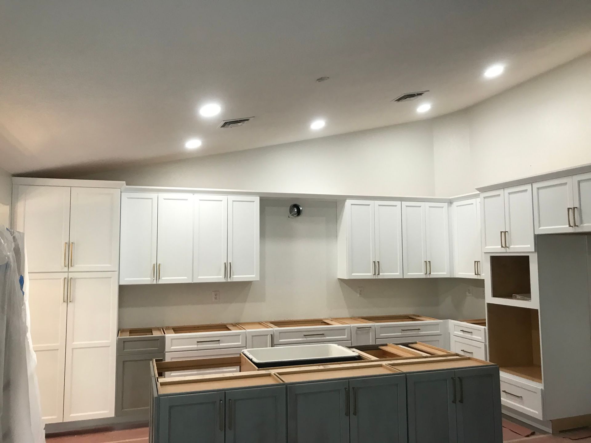 A kitchen with white cabinets and a large island in the middle.