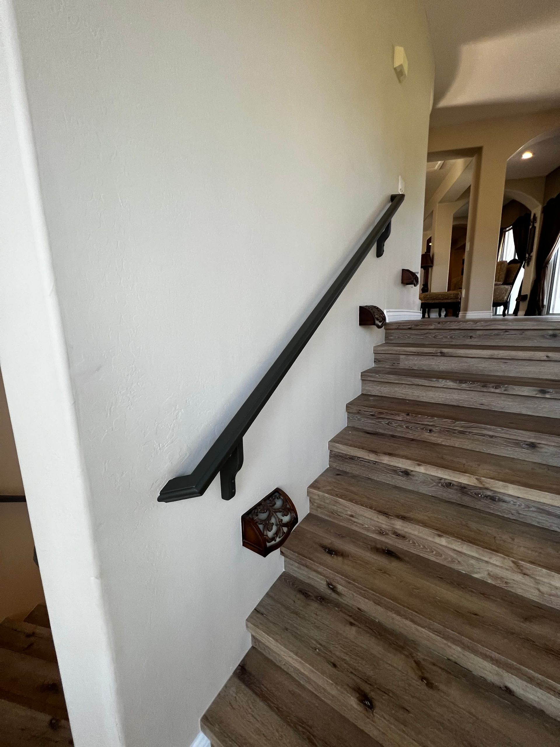 A wooden staircase with a black railing and a white wall