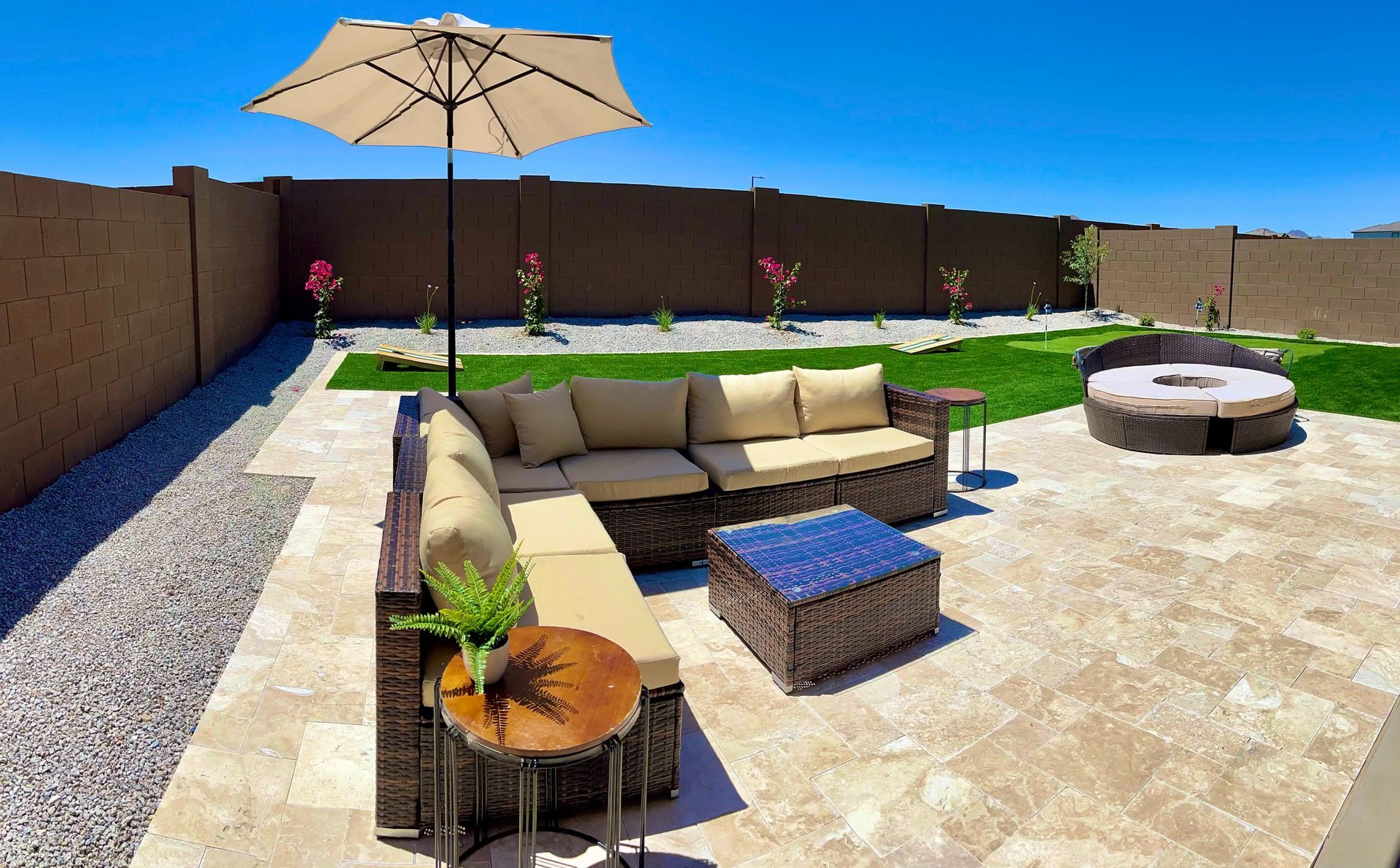 A patio with a couch and umbrella and a fire pit