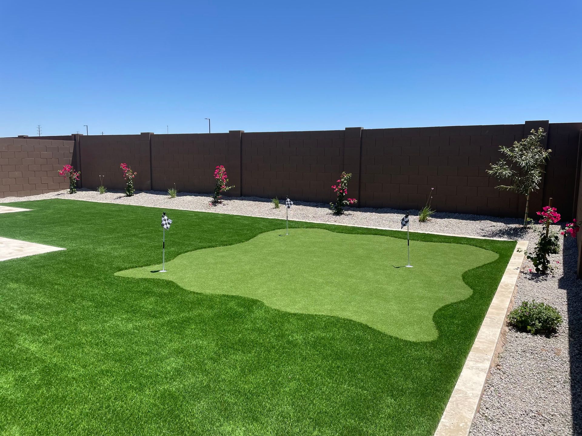 A backyard with a putting green and a fence.