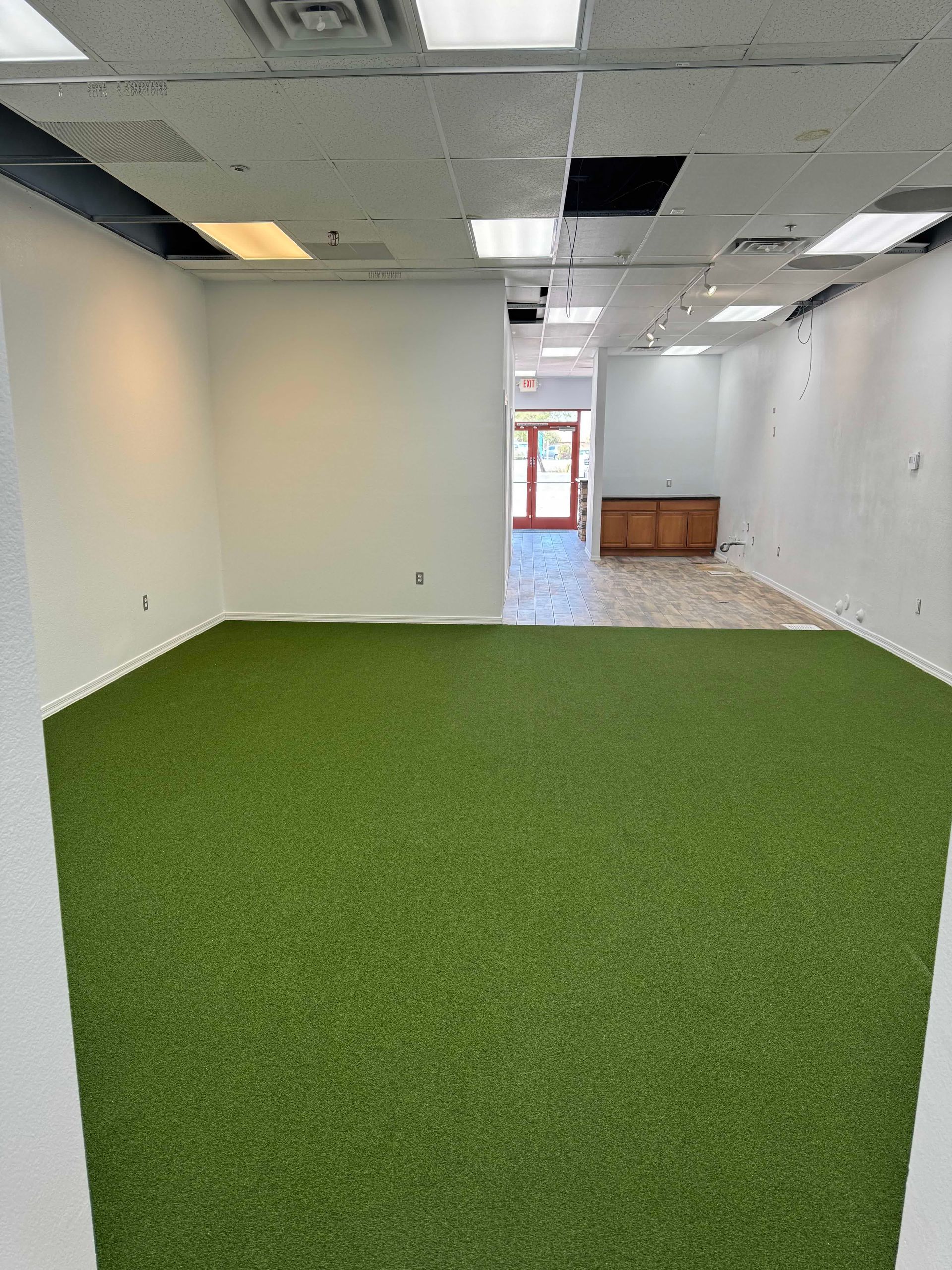 An empty room with a green carpet and white walls.