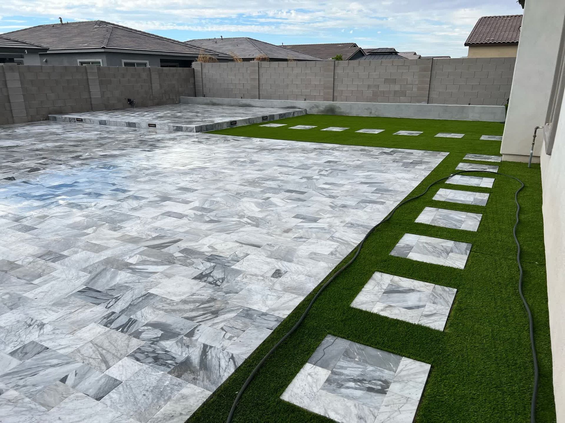 A patio with a walkway and a lawn in front of a house.