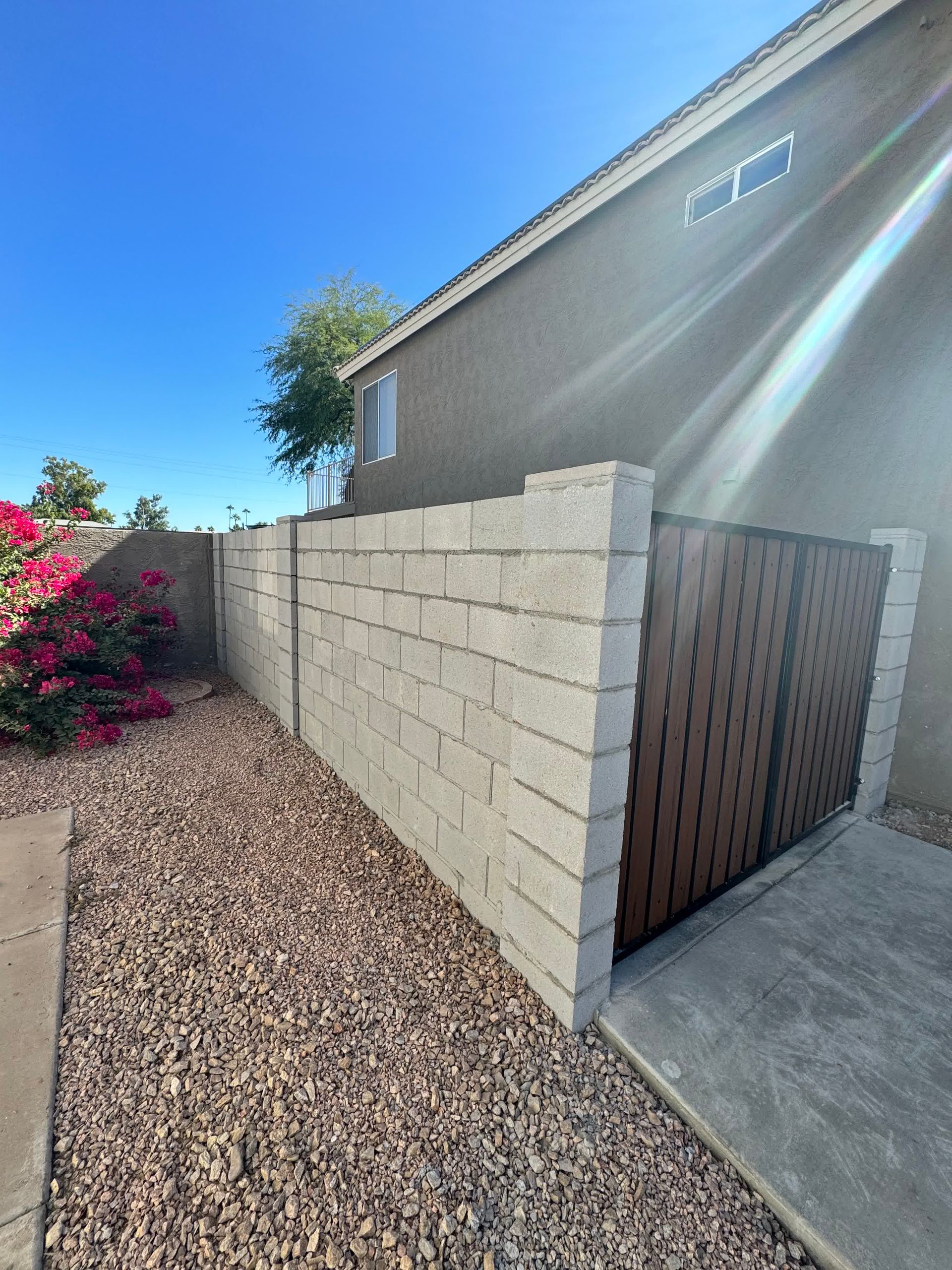A brick wall with a wooden gate in front of a house.