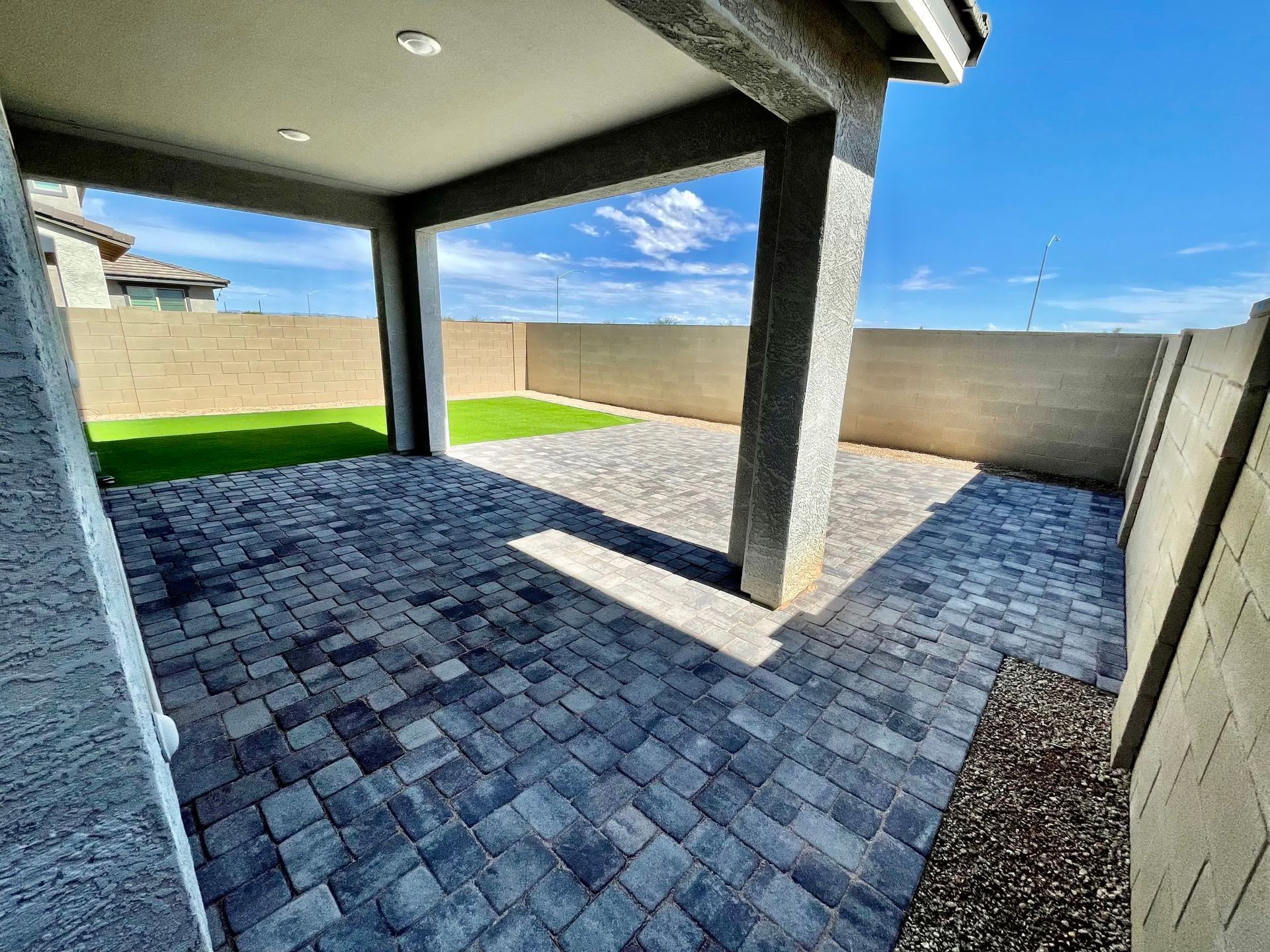 A patio with a brick walkway and a fence in the background.