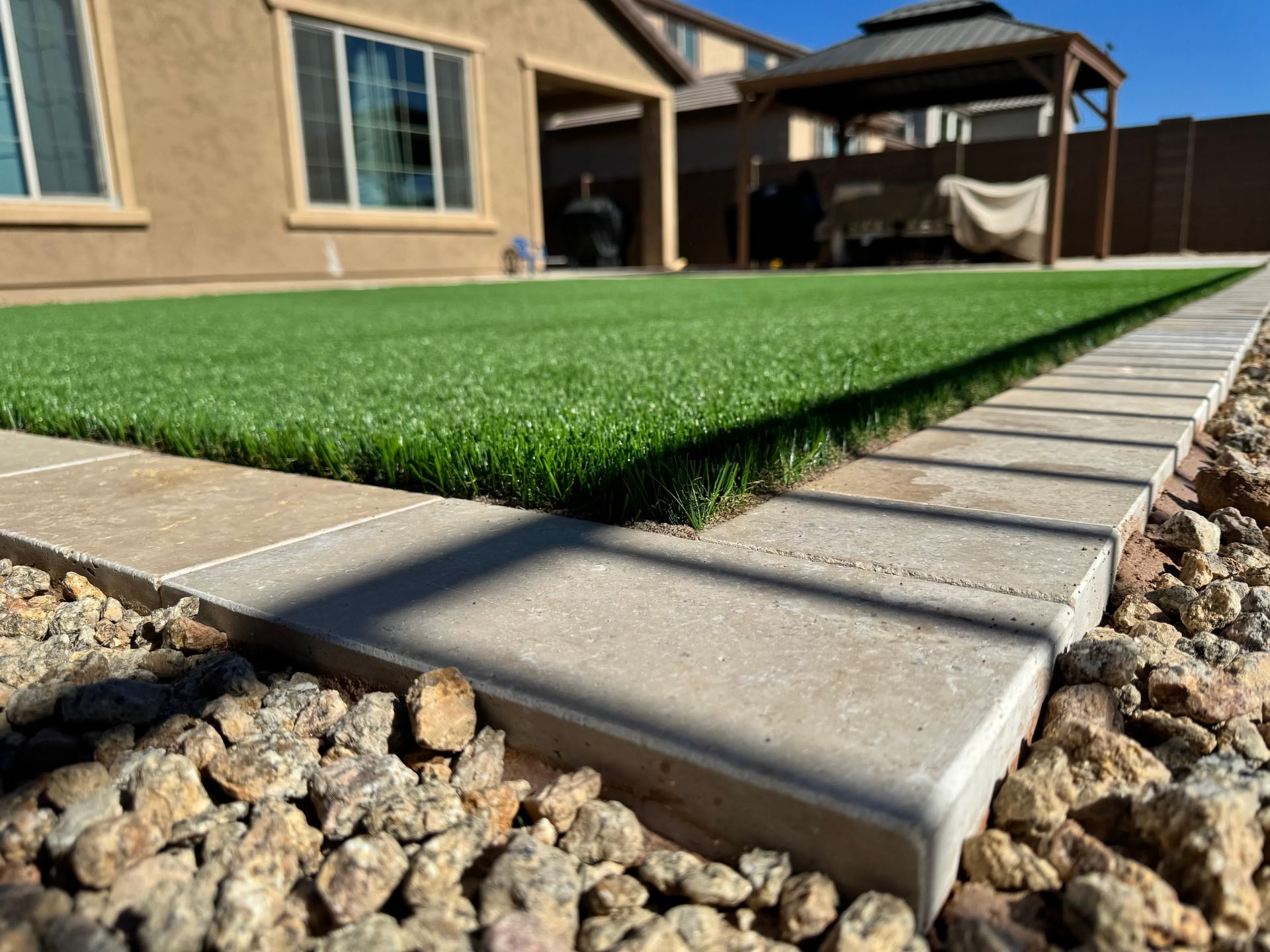 A lawn with a walkway leading to it and a house in the background.