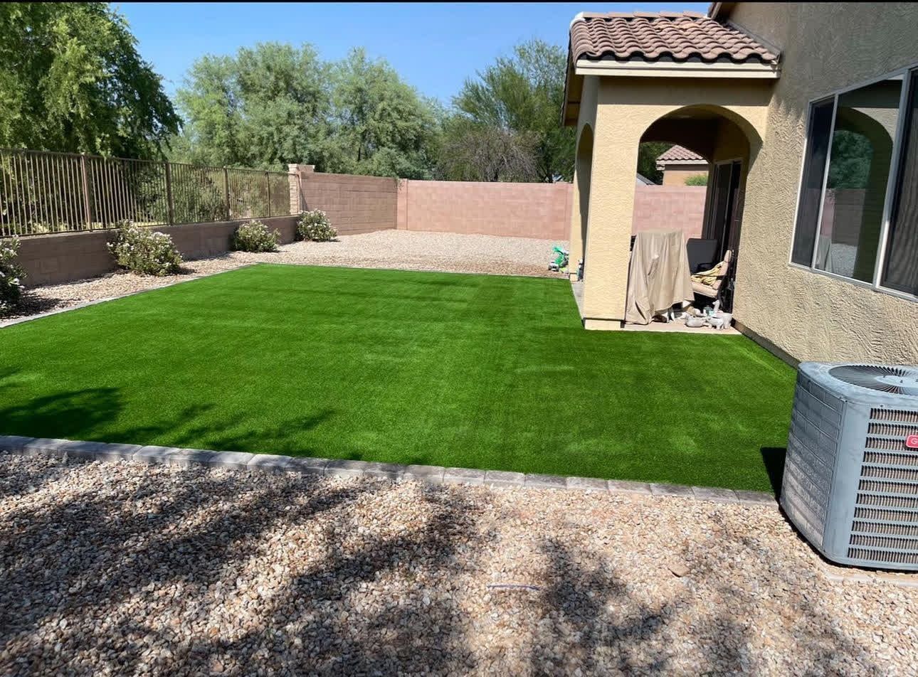 A backyard with a lush green lawn and an air conditioner.