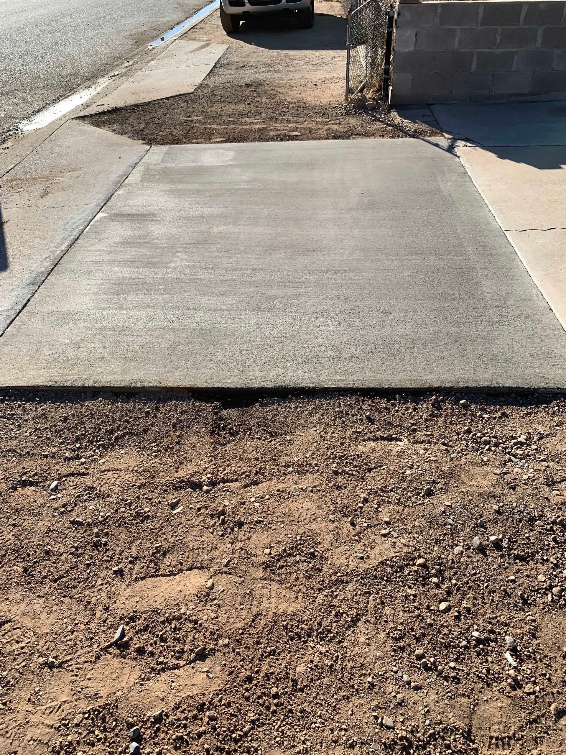 A concrete walkway with a car parked on the side of the road.