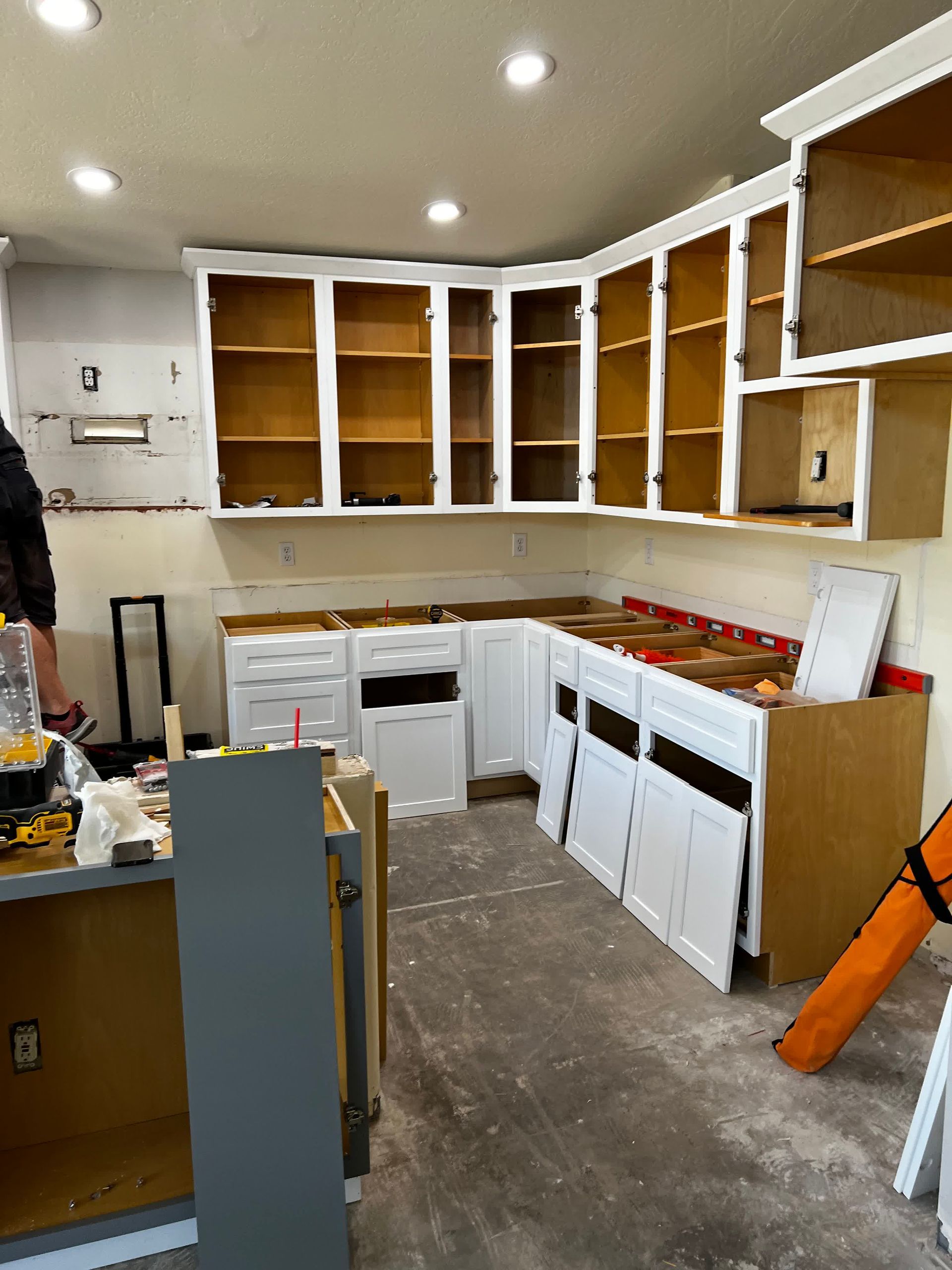 A kitchen is being remodeled with white cabinets and wooden cabinets.
