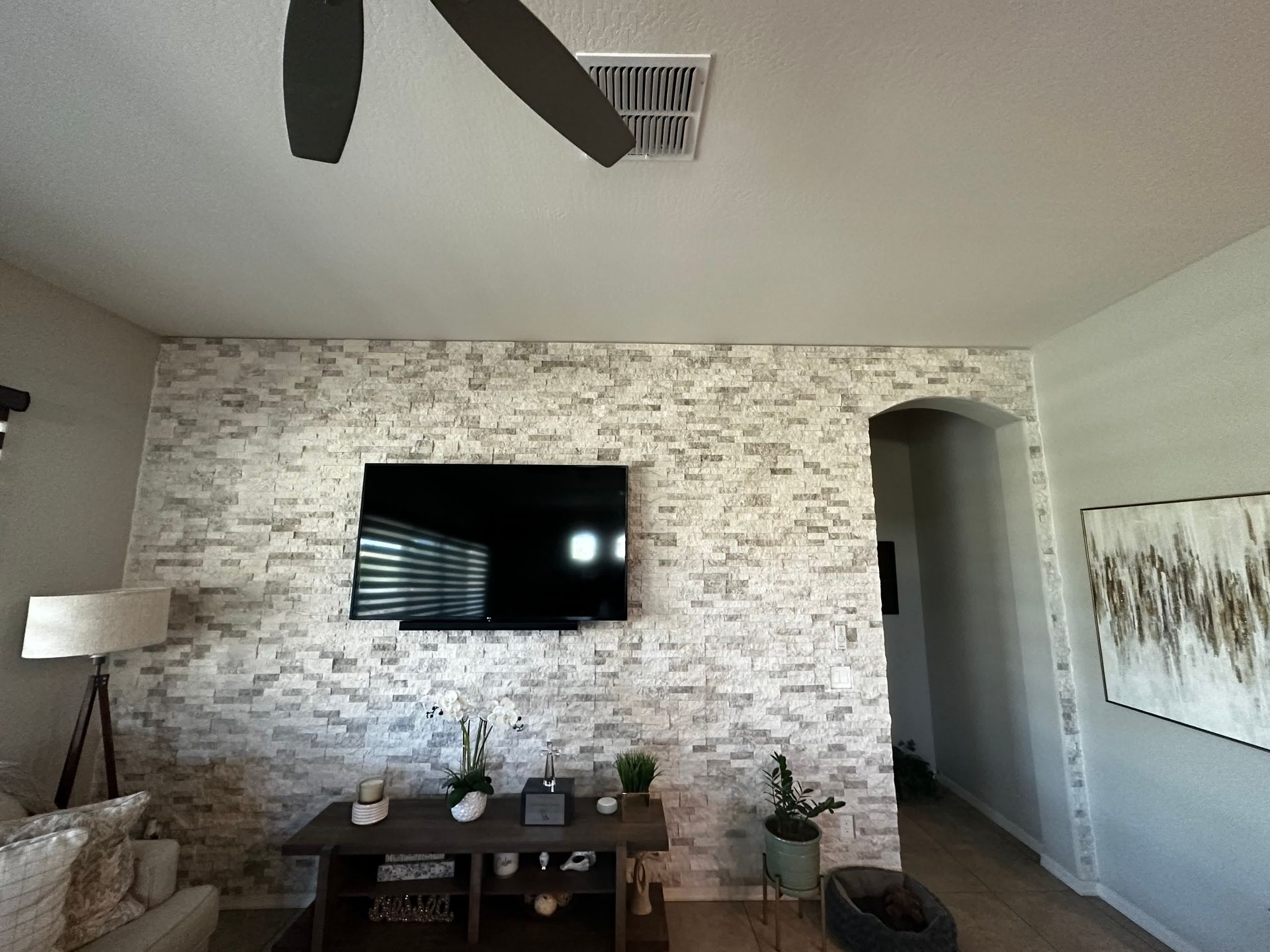 A living room with a ceiling fan and a flat screen tv