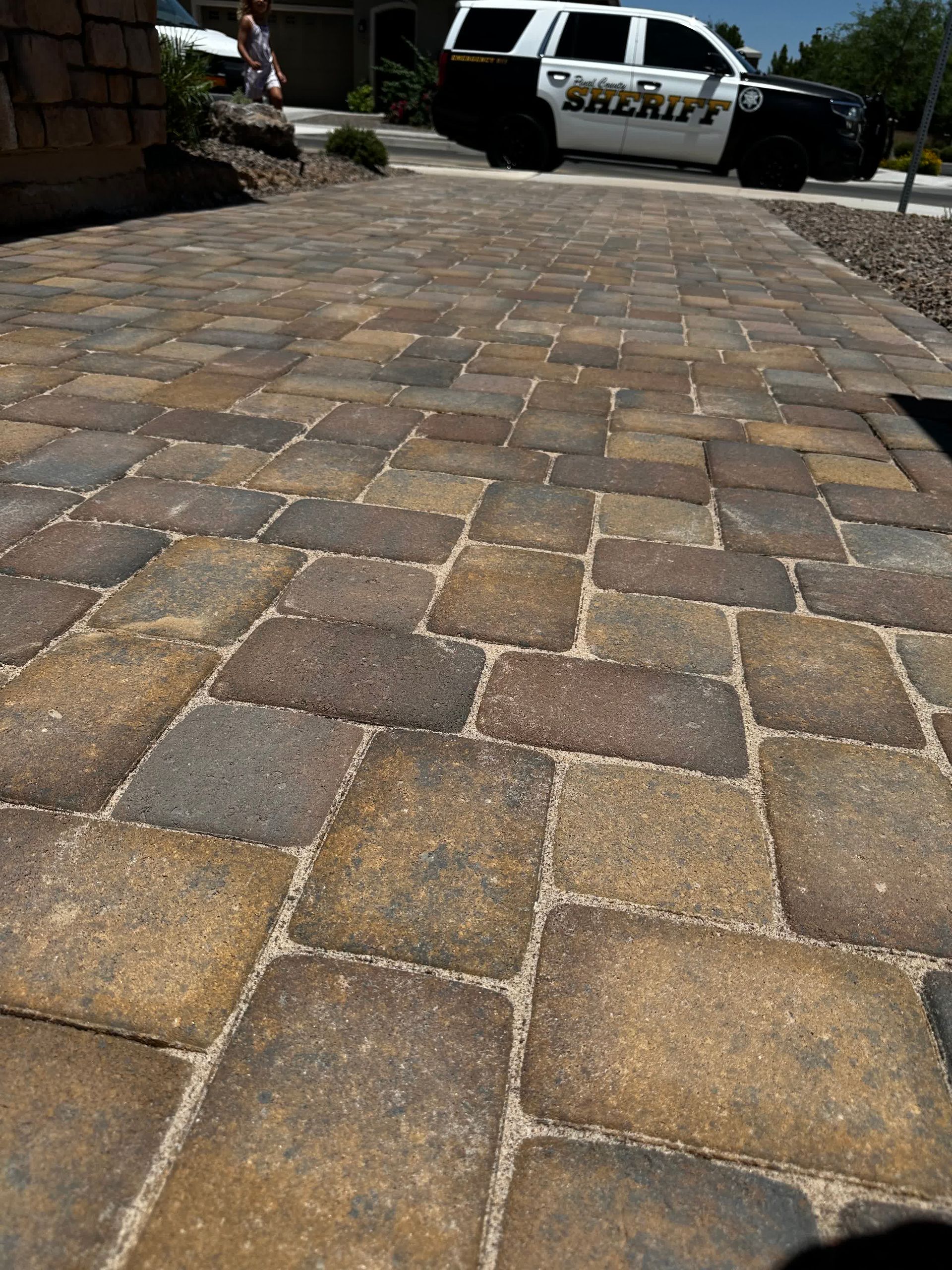 A sheriff 's car is parked on a brick driveway.