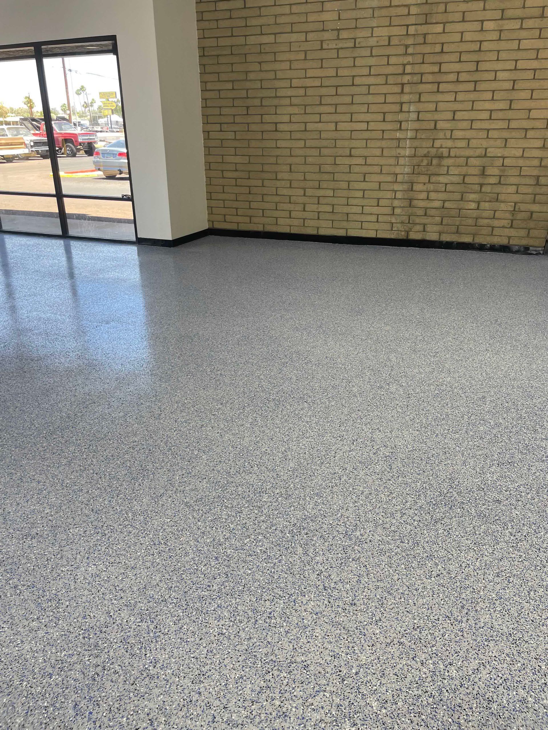 A room with a brick wall and a gray floor.
