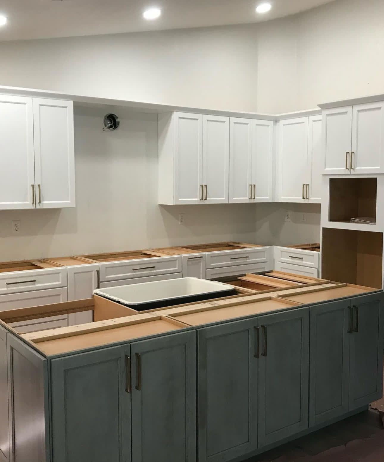 A kitchen with white cabinets and a large island in the middle.