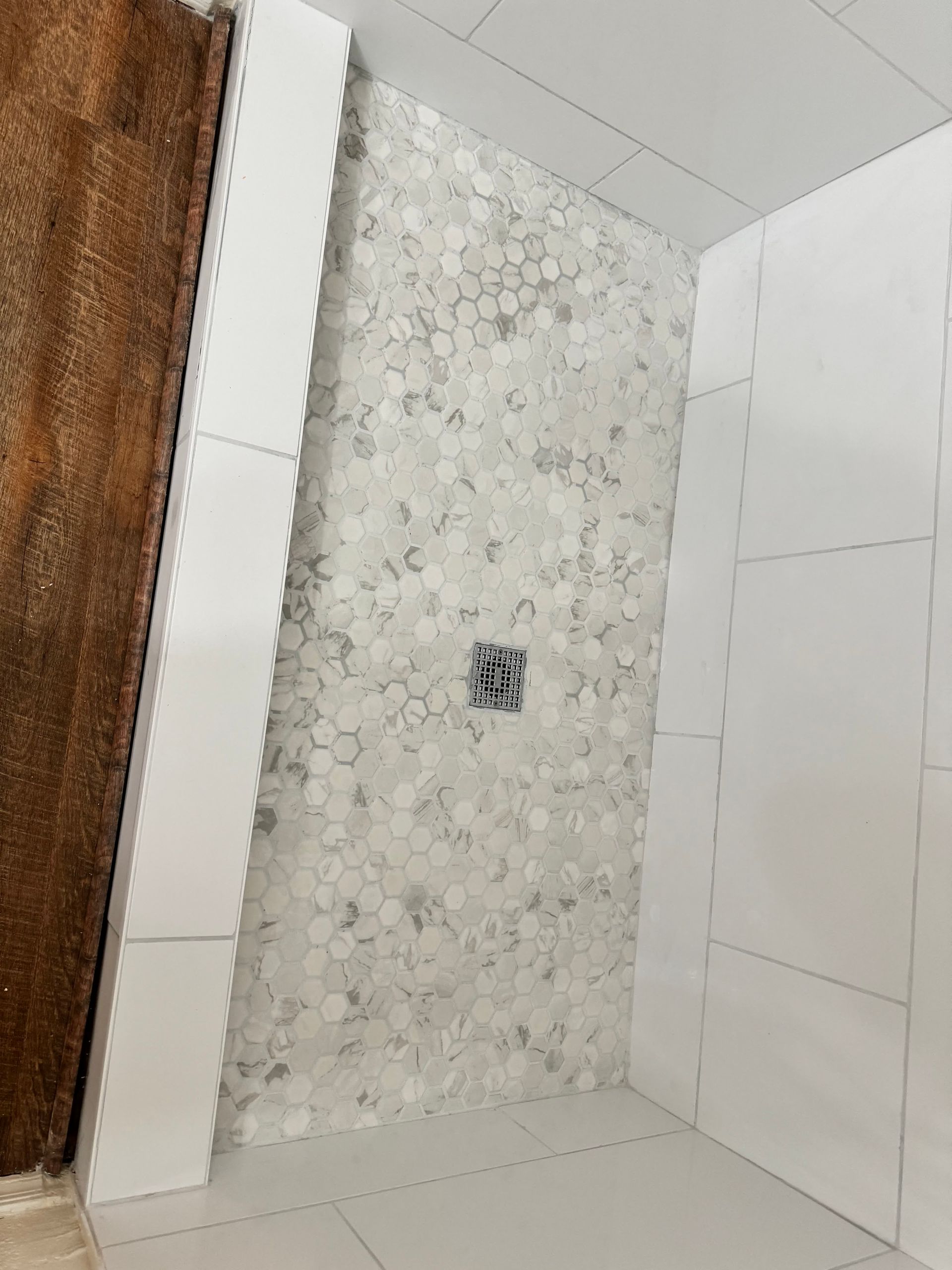 A bathroom with white tiles and a walk in shower.