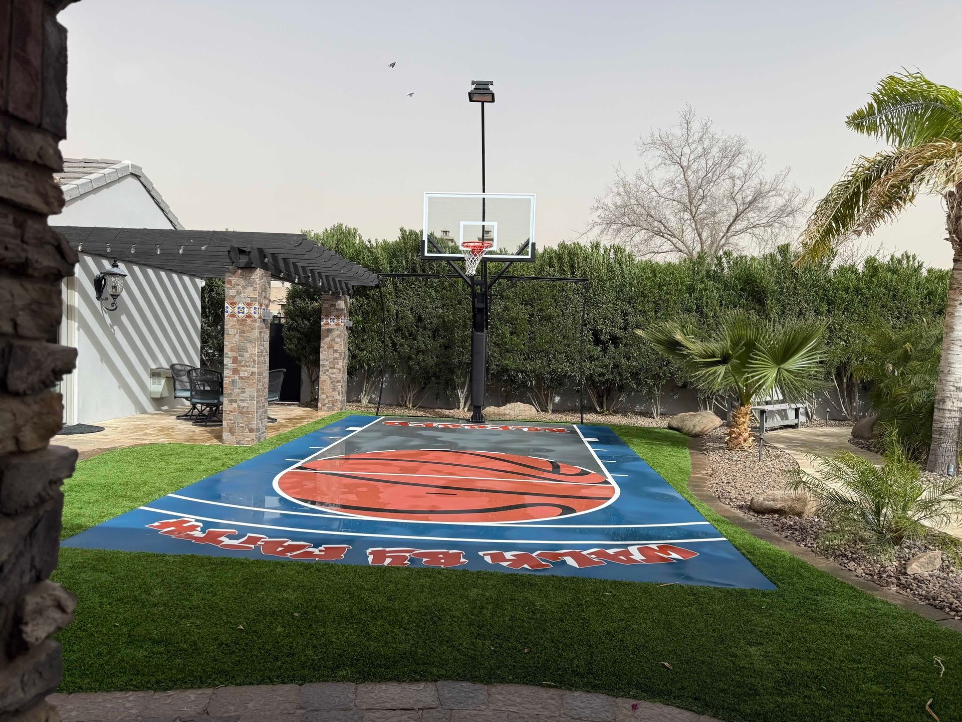 There is a basketball court in the backyard of a house.